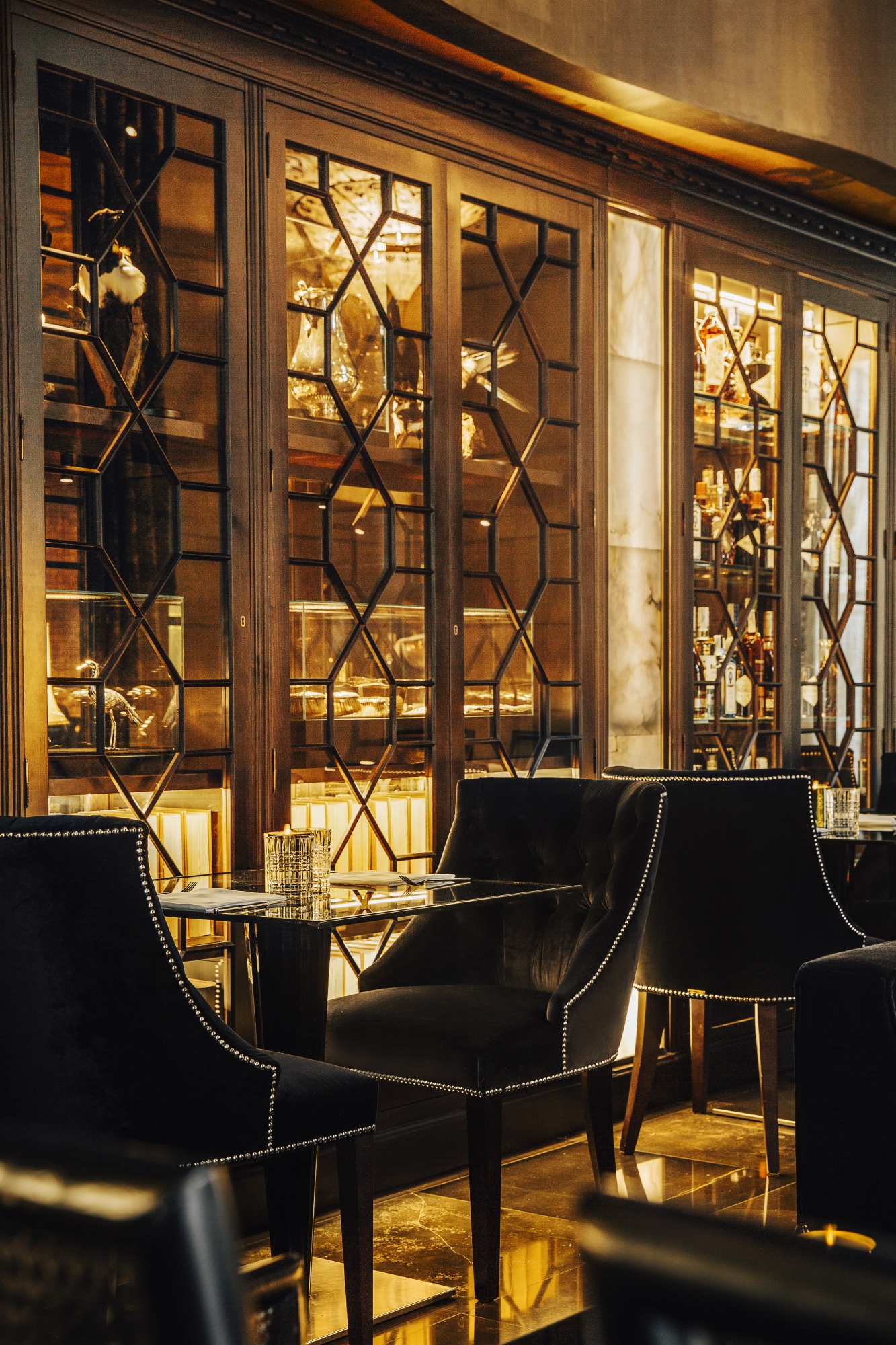 Un bar interior con asientos tapizados negros y ventanales con luz cálida.