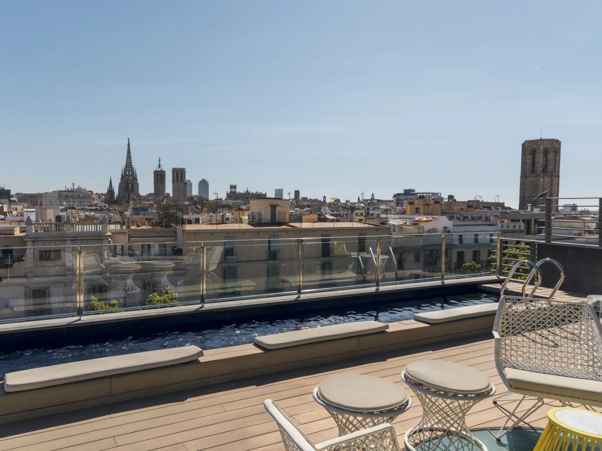 Se ve una terraza con tumbonas, mesas y sillas junto a una piscina exterior al aire libre.
