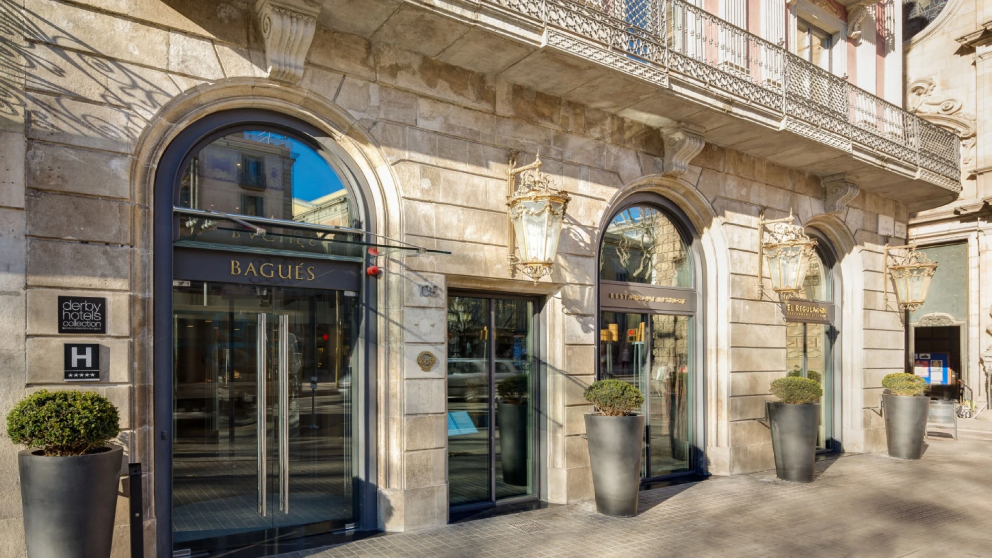 Se ve la entrada principal con arcos de piedra y ventanas sobre la fachada de un edificio histórico.