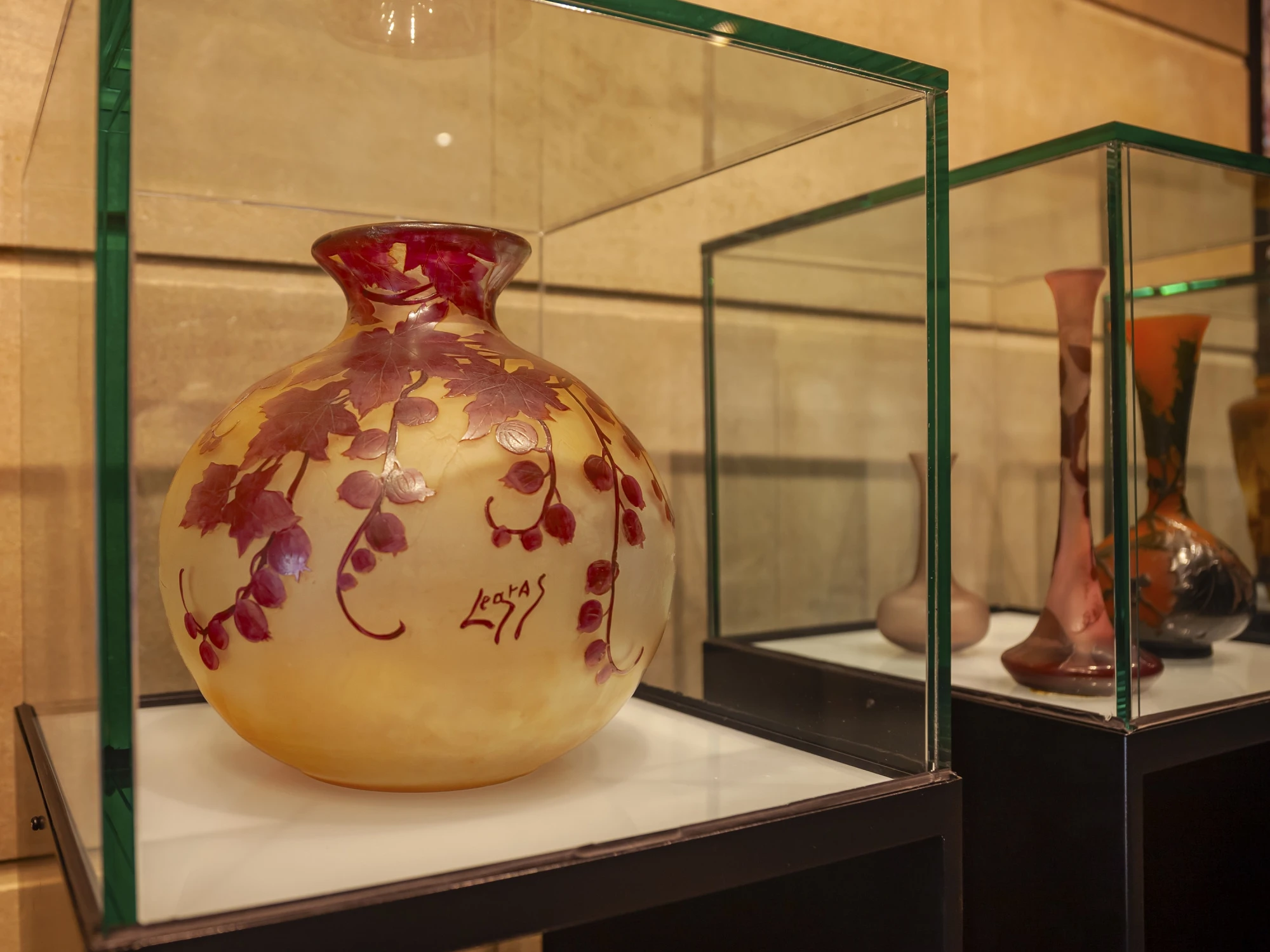Se ven jarrones decorativos dentro de vitrinas de cristal en una sala tipo museo.