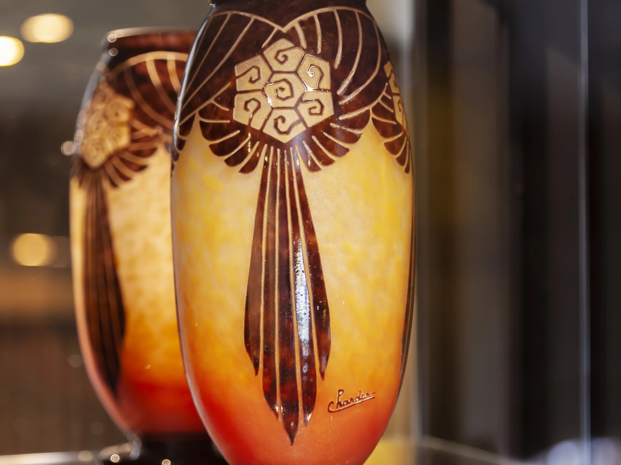 Dos jarrones decorativos con estampados y acabado brillante se exhiben en una vitrina iluminada.
