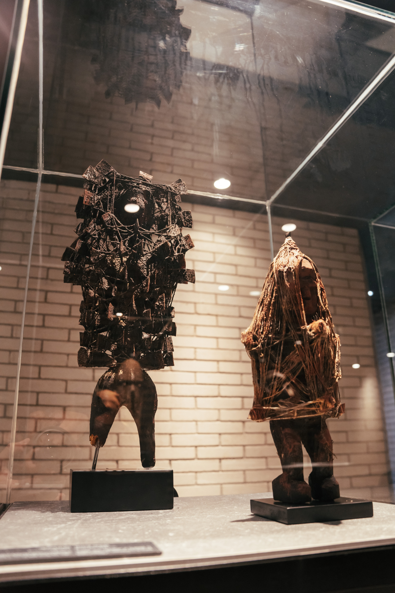 Se ve una sala con paredes de ladrillo y dos esculturas sobre pedestales de exhibición.