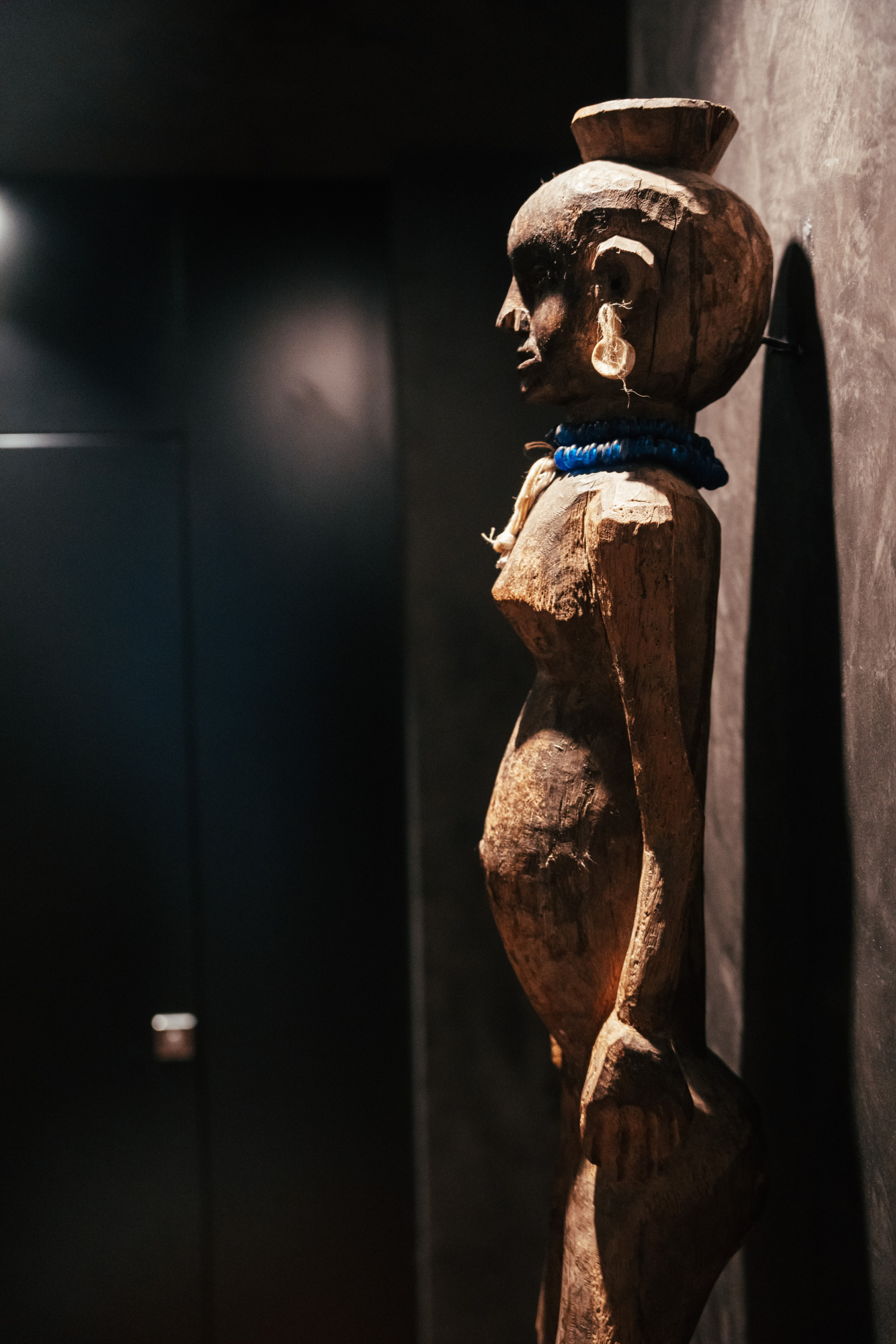 Se ve una escultura de madera tallada con detalles decorativos sobre un fondo oscuro.