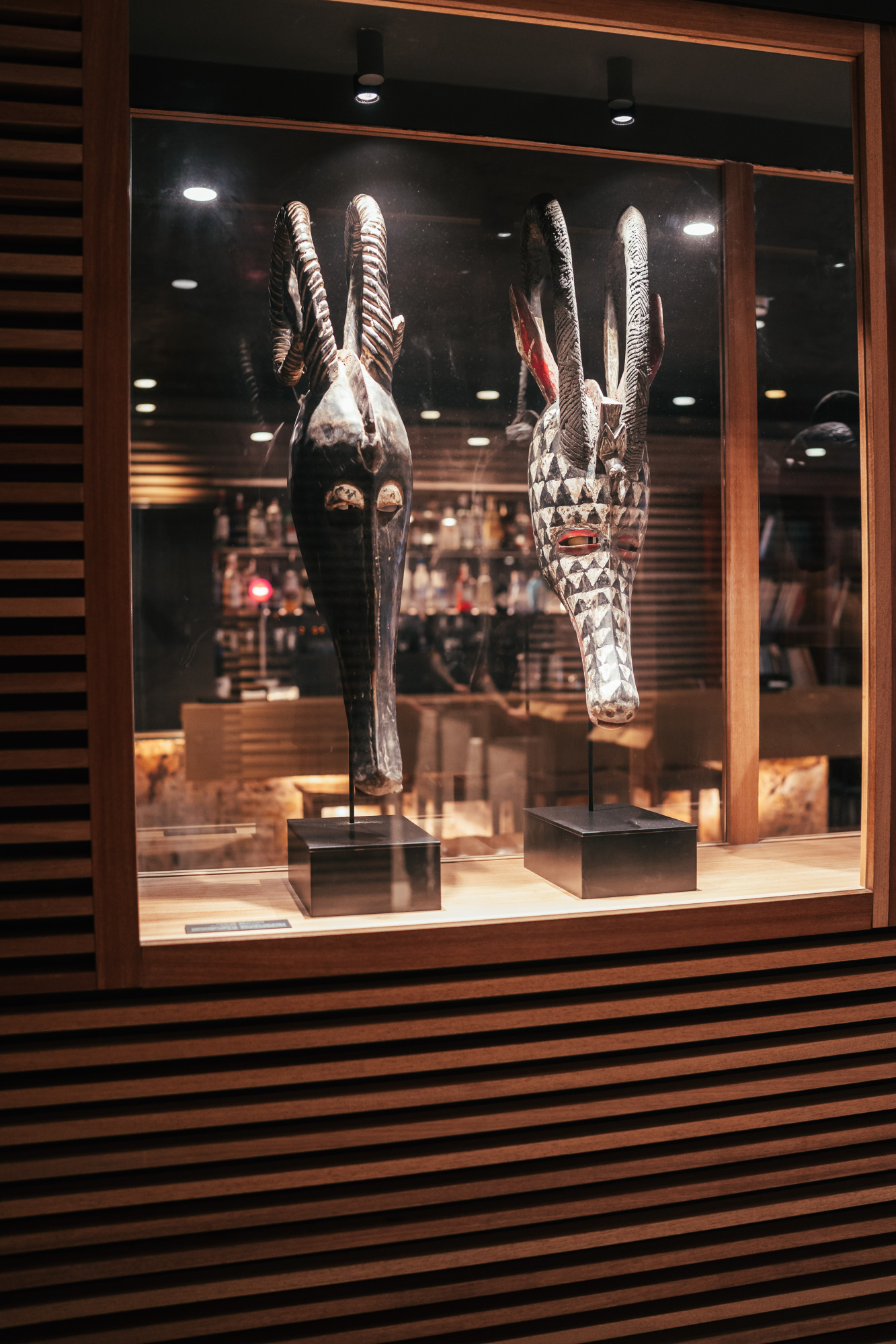 Se ve una vitrina con esculturas africanas iluminadas en una sala interior.