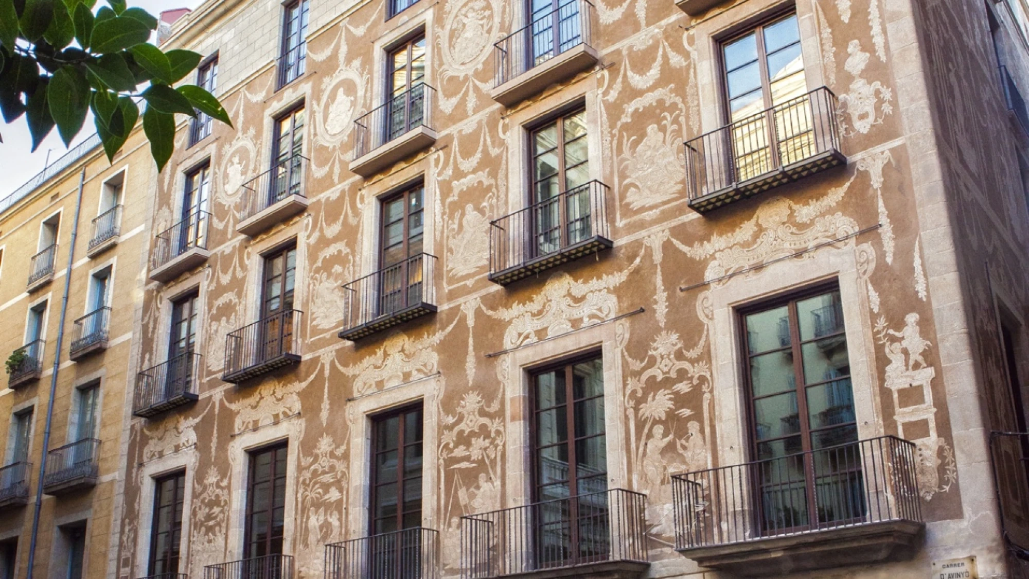 Se ve la fachada de un edificio de varios pisos con ventanas y balcones de hierro.