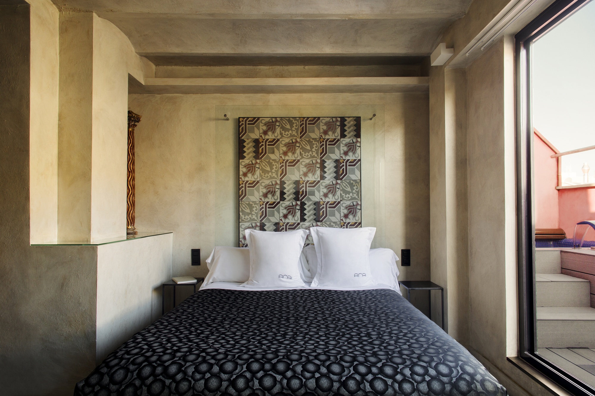 Se ve una cama doble con almohadas y una ventana junto a un balcón en una suite.