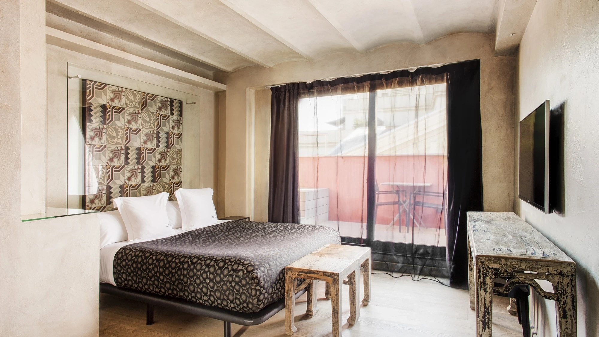 Se ve una suite con cama y una puerta de balcón con cortinas.