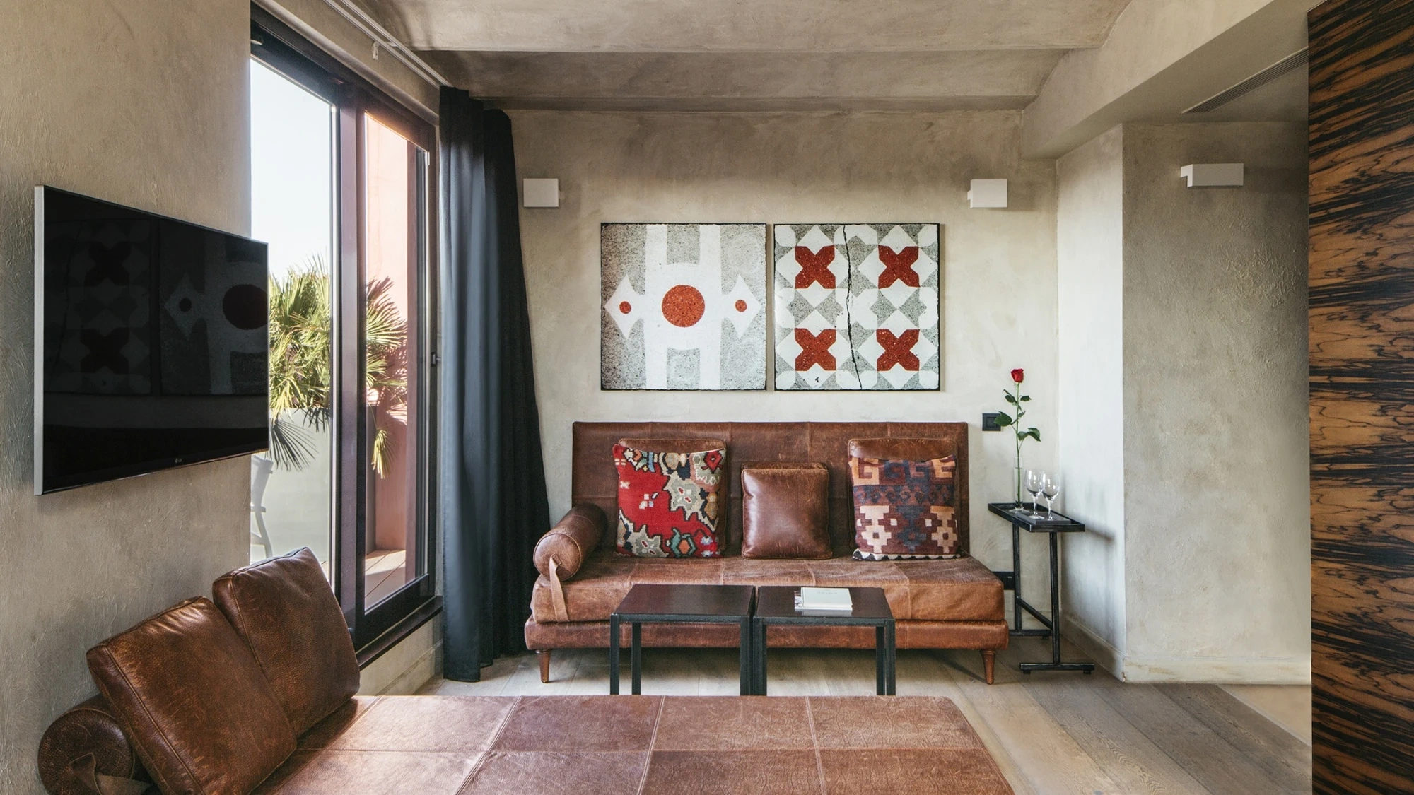Se ve una sala de estar con un sofá de cuero, una mesa baja y una ventana junto a la pared.