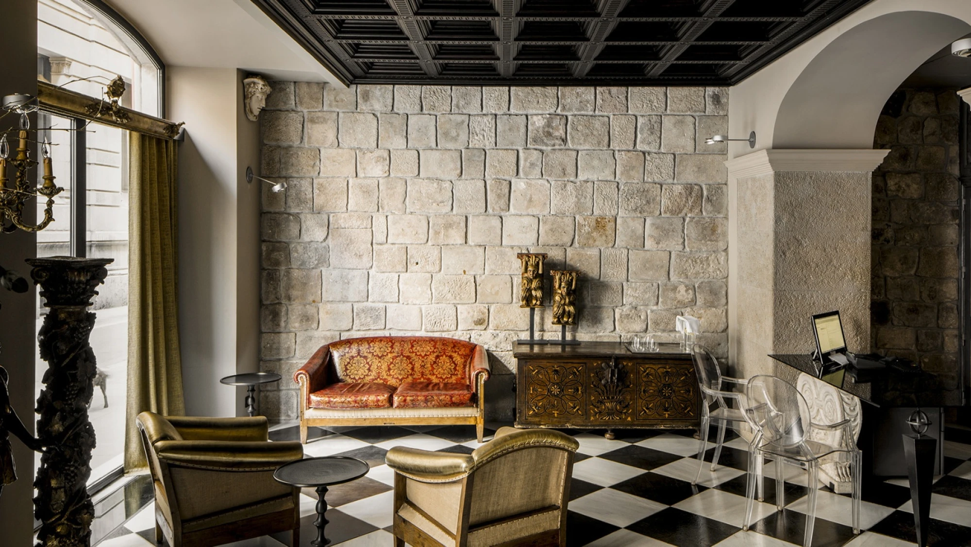 El vestíbulo muestra sillones y una pared de piedra con arcos.