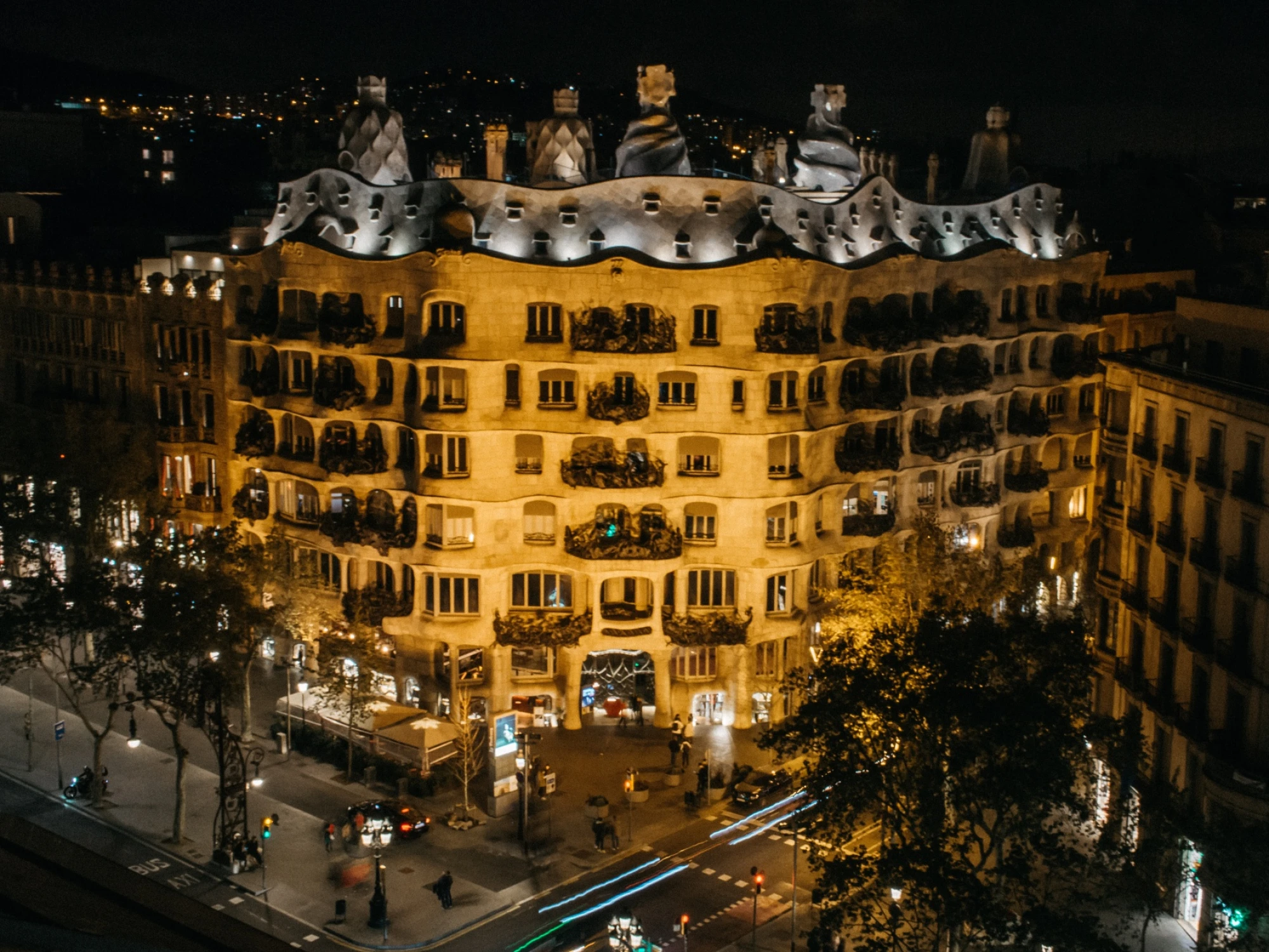 Vista nocturna de un edificio histórico iluminado con balcones y luces en las ventanas.