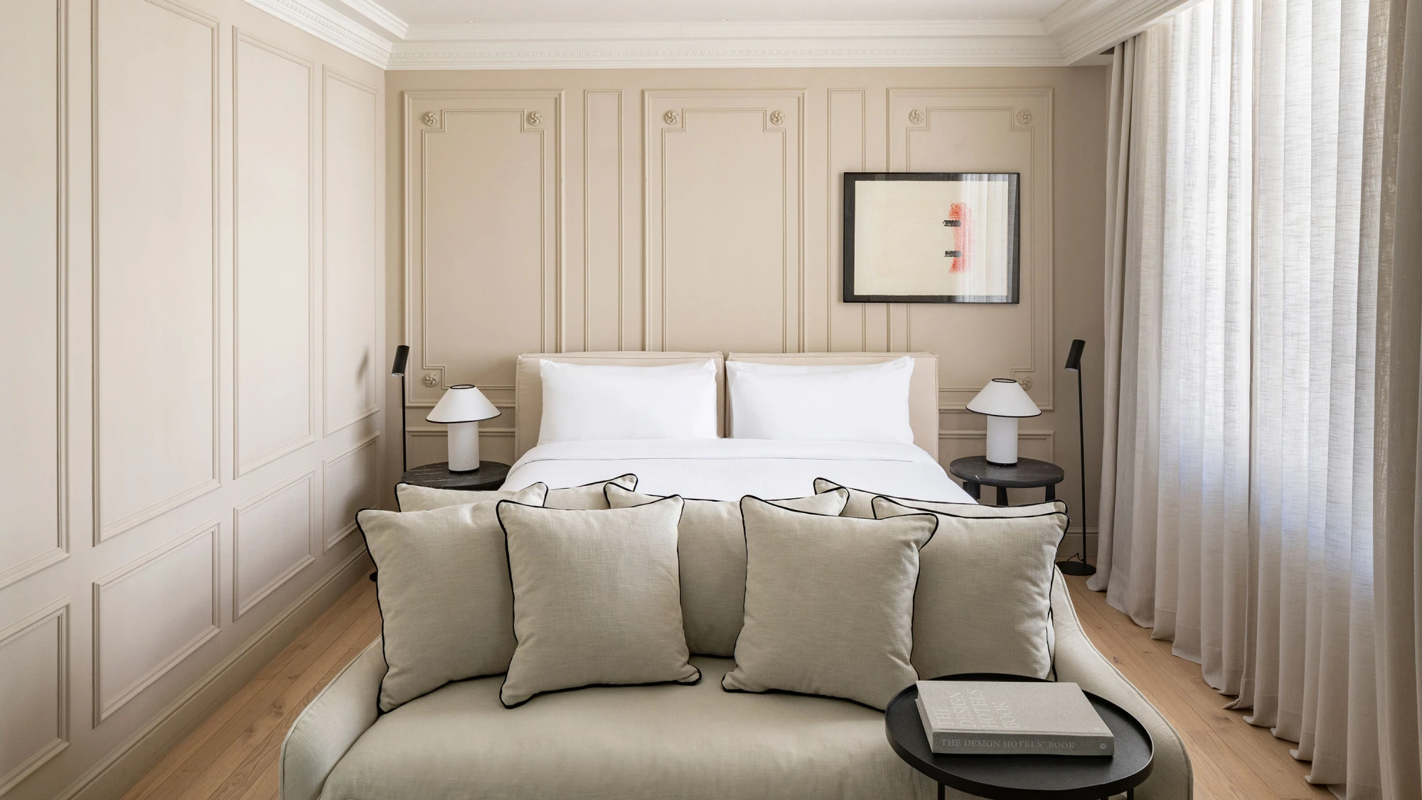 Un dormitorio luminoso con cama doble, mesitas de noche y cortinas claras.