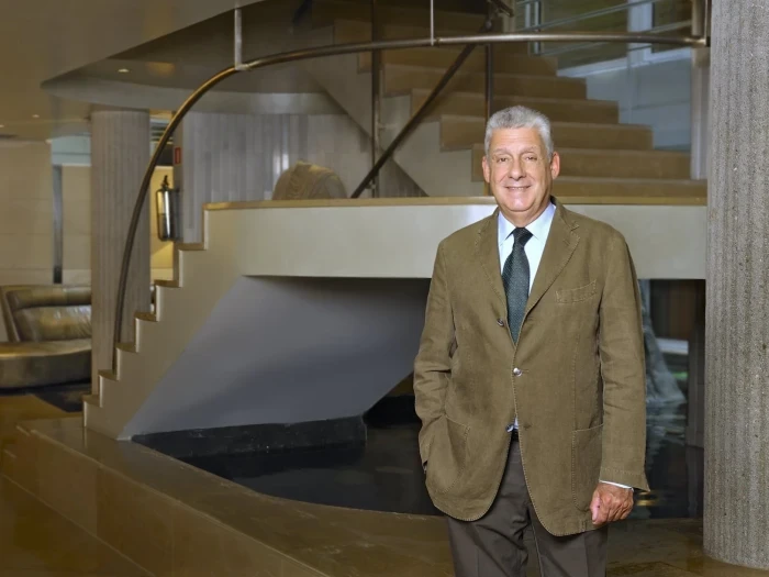 Se ve una zona de recepción interior con escaleras y un hombre de pie junto al mostrador.
