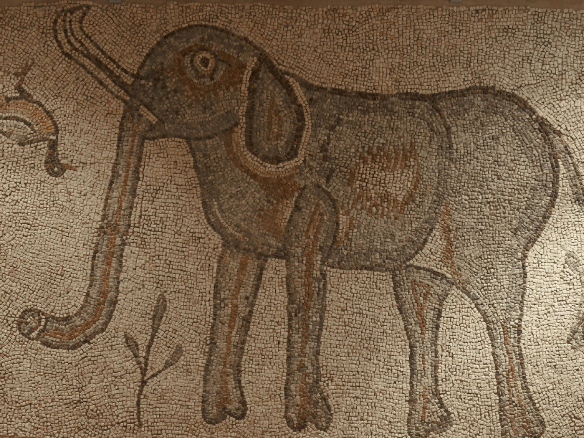 Se ve un mosaico romano con un elefante representado en tonos marrones y dorados sobre fondo beige.