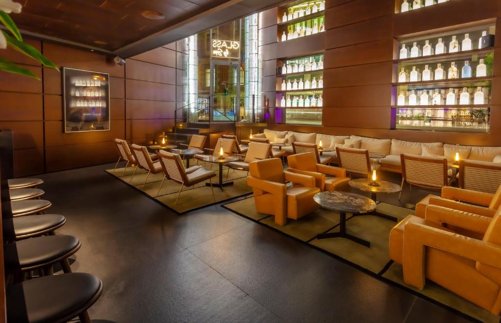 Restaurante interior con mesas, sillas tapizadas y velas encendidas junto a una barra con botellas