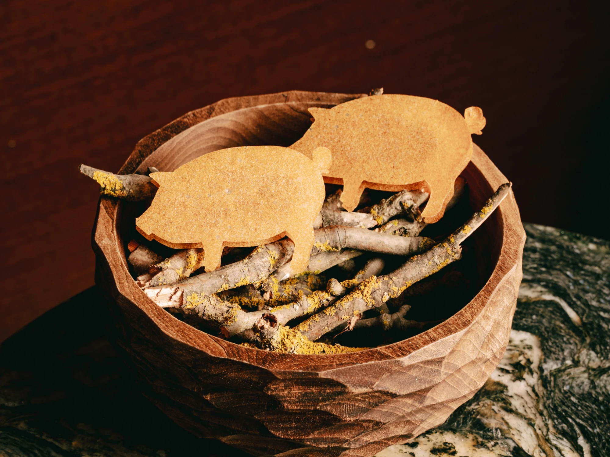 Se ven figuras de pan tostado con forma de cerdo sobre una mesa con pequeños elementos decorativos.
