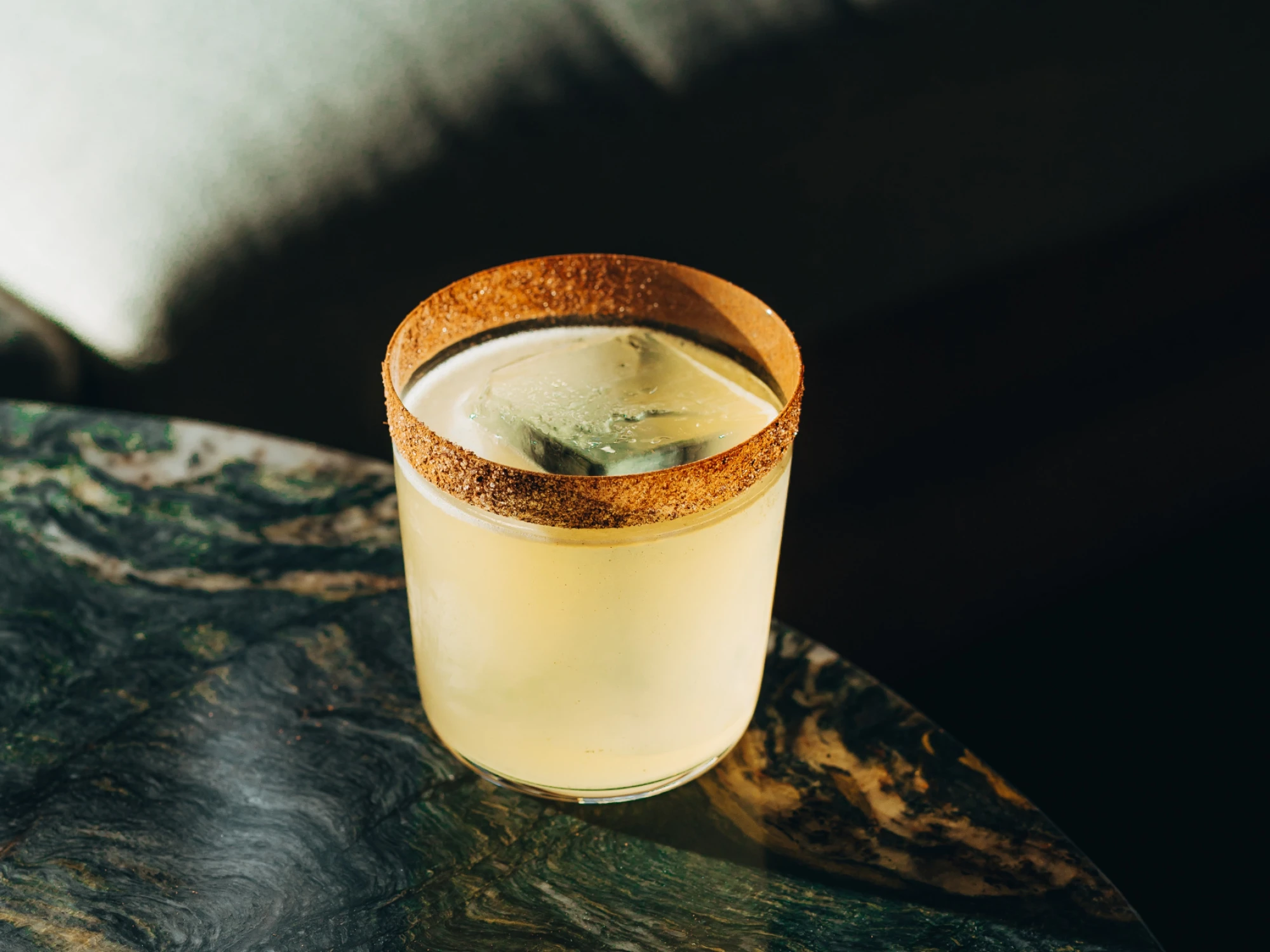 Sirven una copa con un cocktail Margarita sobre una superficie oscura.