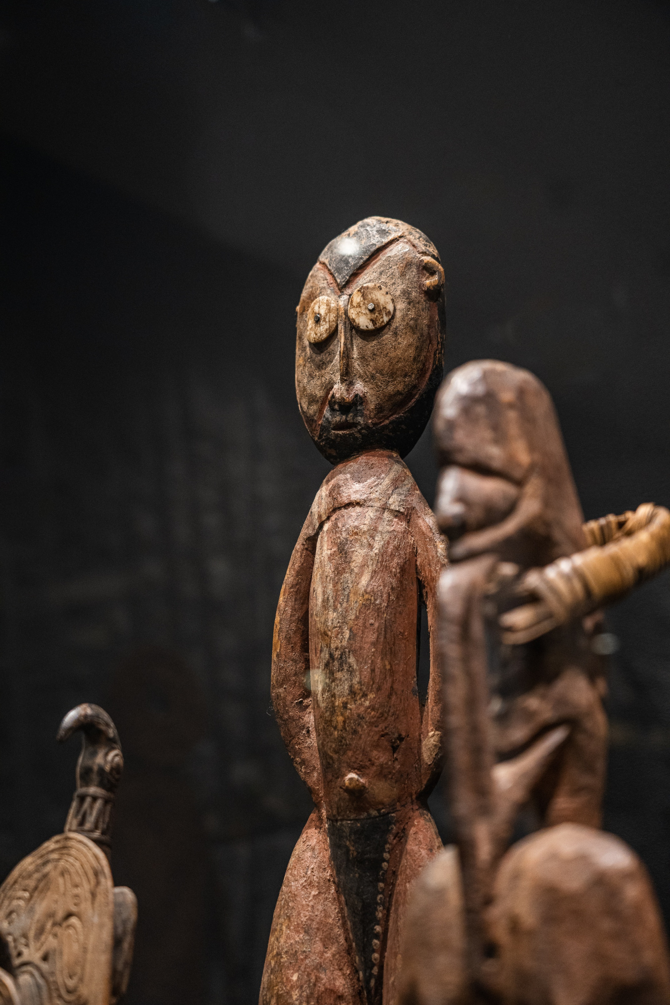 Se ven varias esculturas de figuras humanas de estilo antiguo sobre un fondo oscuro.