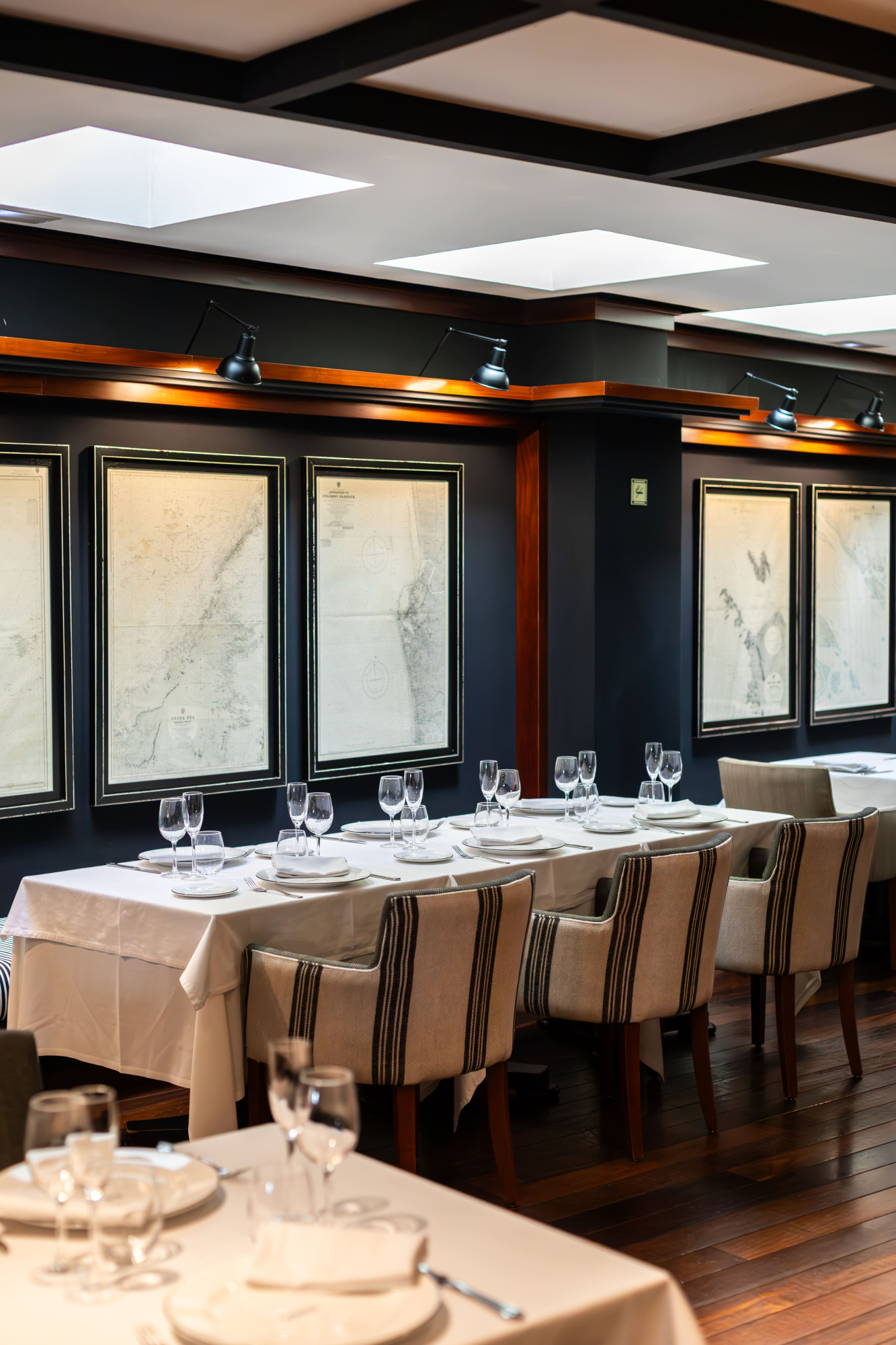 Se ve una mesa con mantelería y vajilla servida en un comedor con cuadros en la pared.
