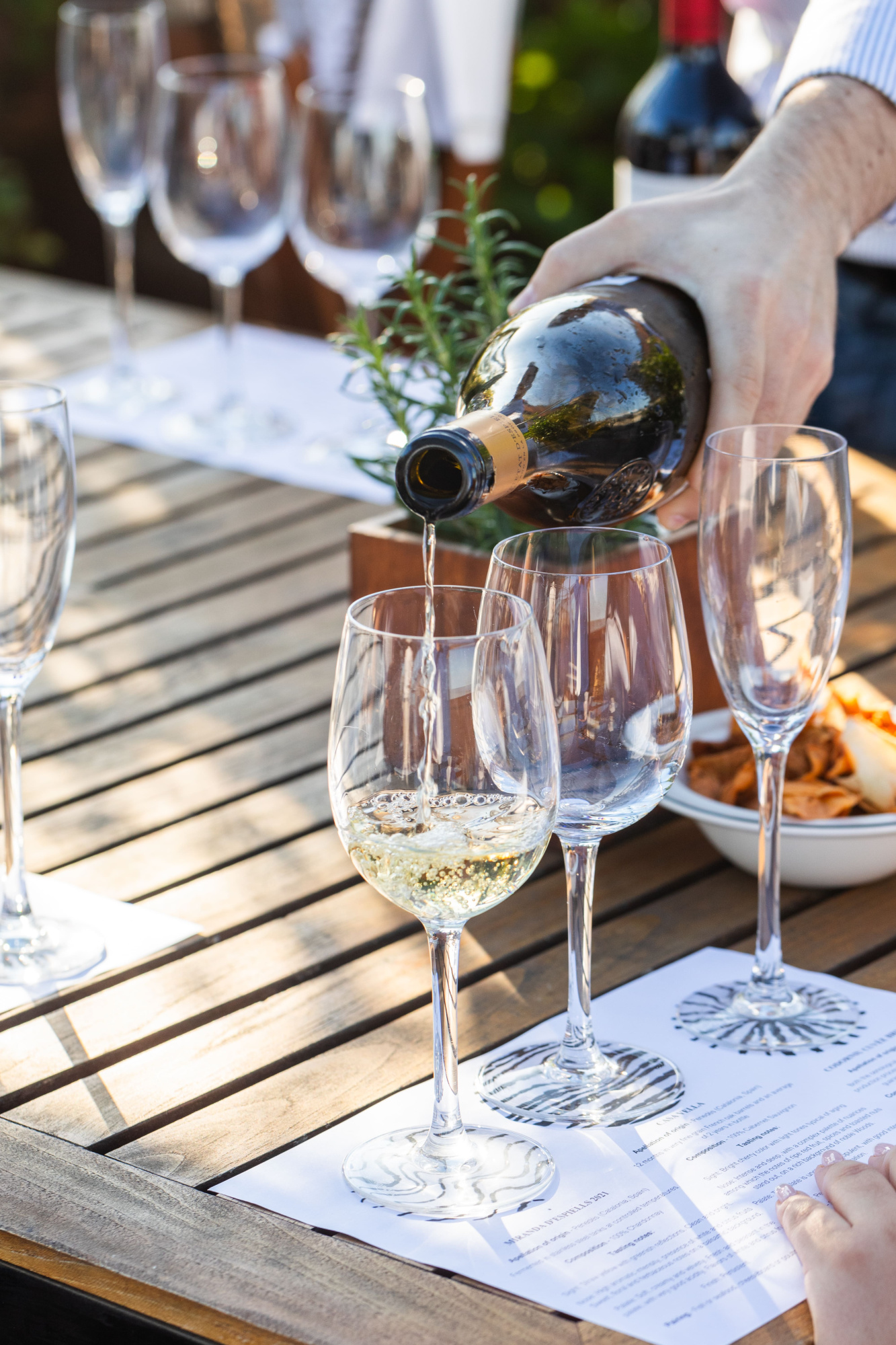 Se sirve vino desde una botella en copas sobre una mesa con mantel blanco.