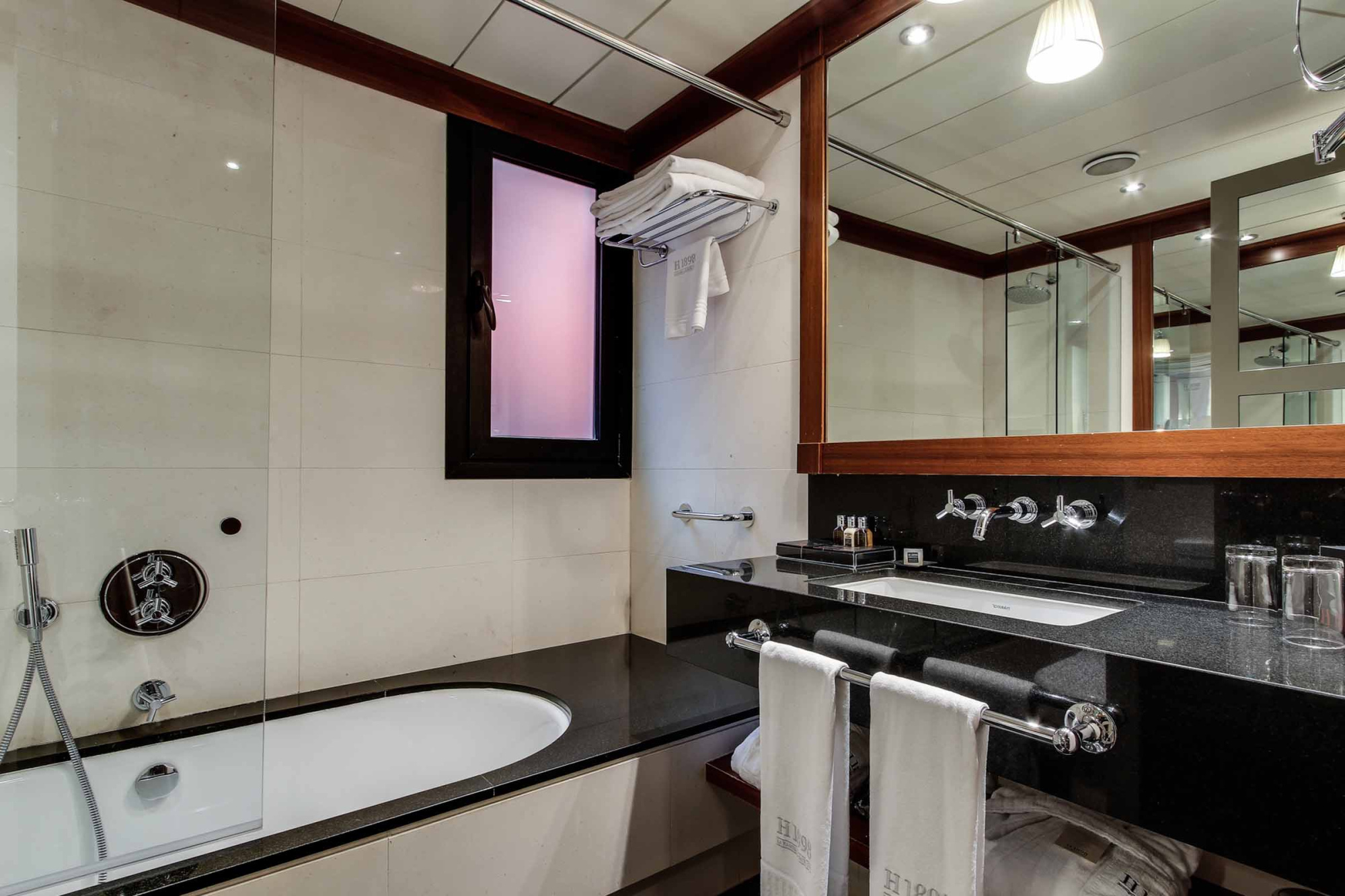 A bathroom is shown with a bathtub, double sink, and a mirror with lighting.