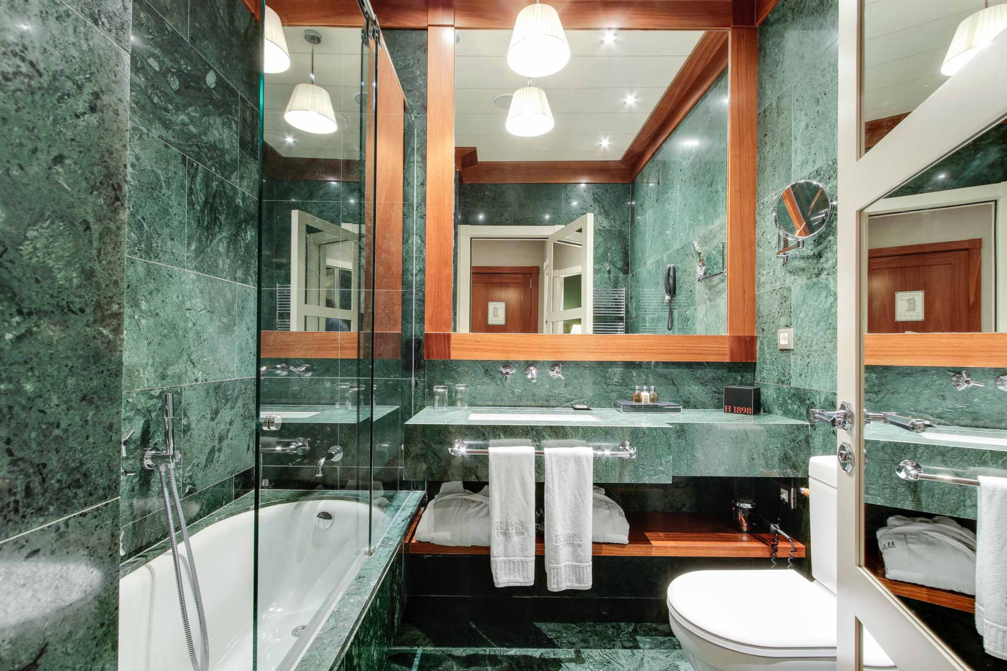 Si vede un bagno con vasca, doppio lavabo e specchio con illuminazione integrata.