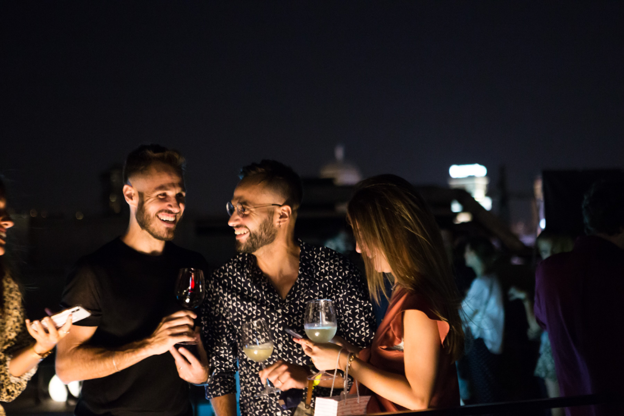 Varias personas brindan con copas en un evento social al aire libre por la noche.