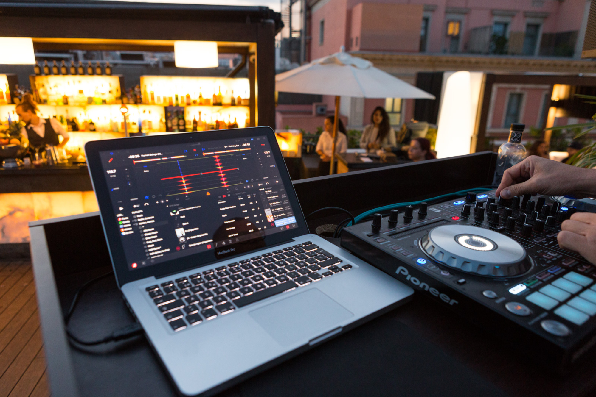 Se ve una mesa con un portátil y un controlador de DJ en un evento al aire libre.