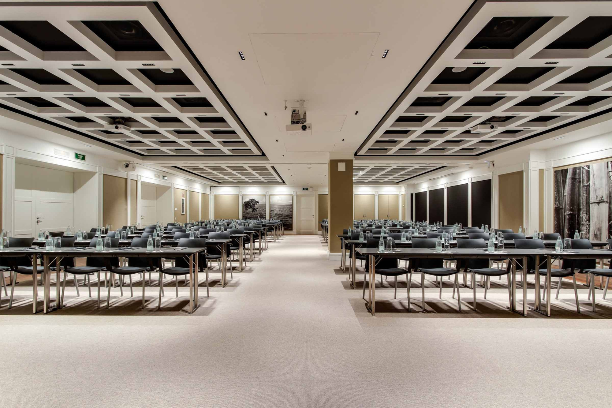 Se ve una sala de reuniones amplia con mesas y sillas dispuestas en filas.