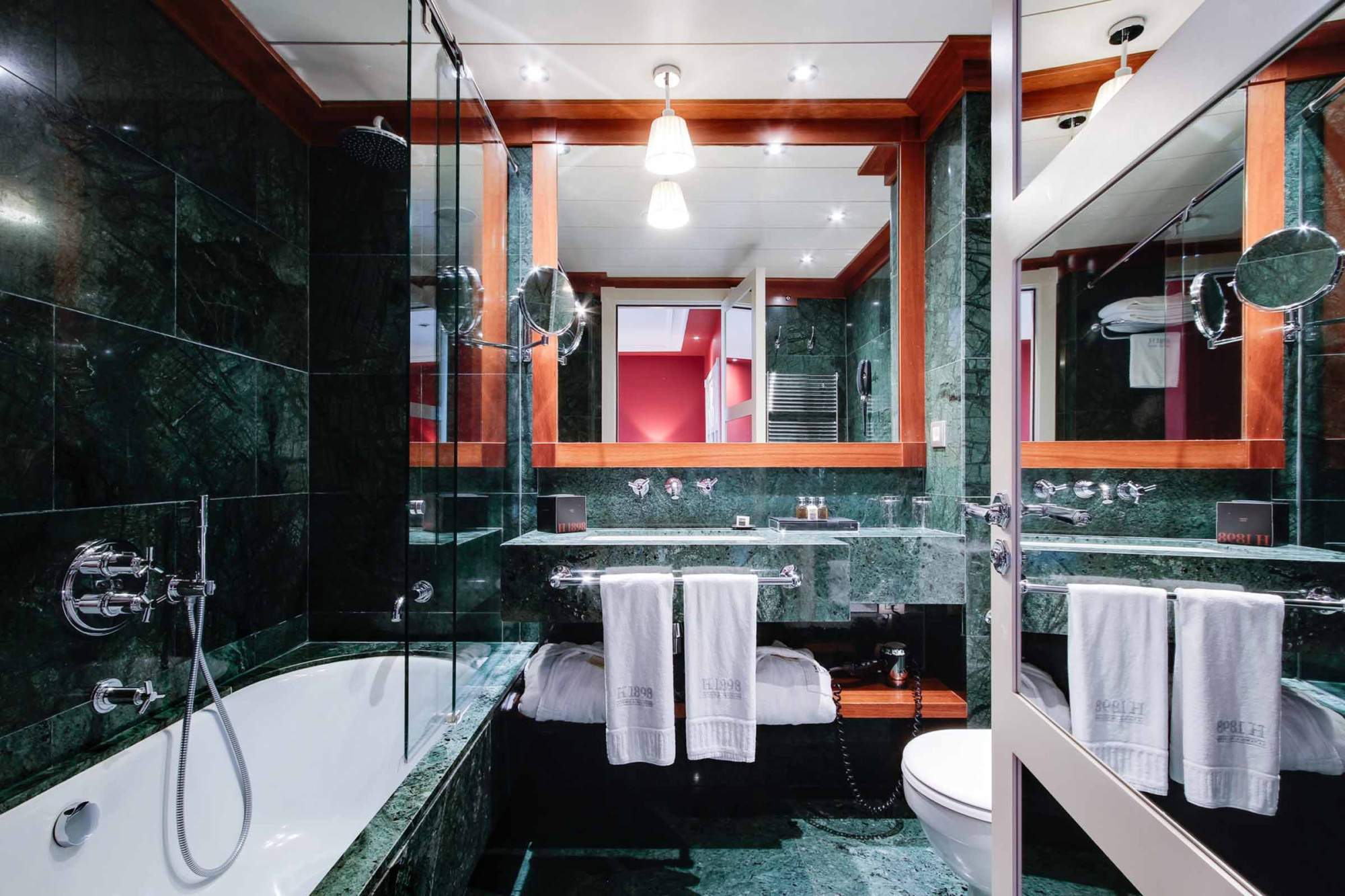 Se ve un baño moderno con bañera, ducha de cristal y lavabo con toallas blancas.
