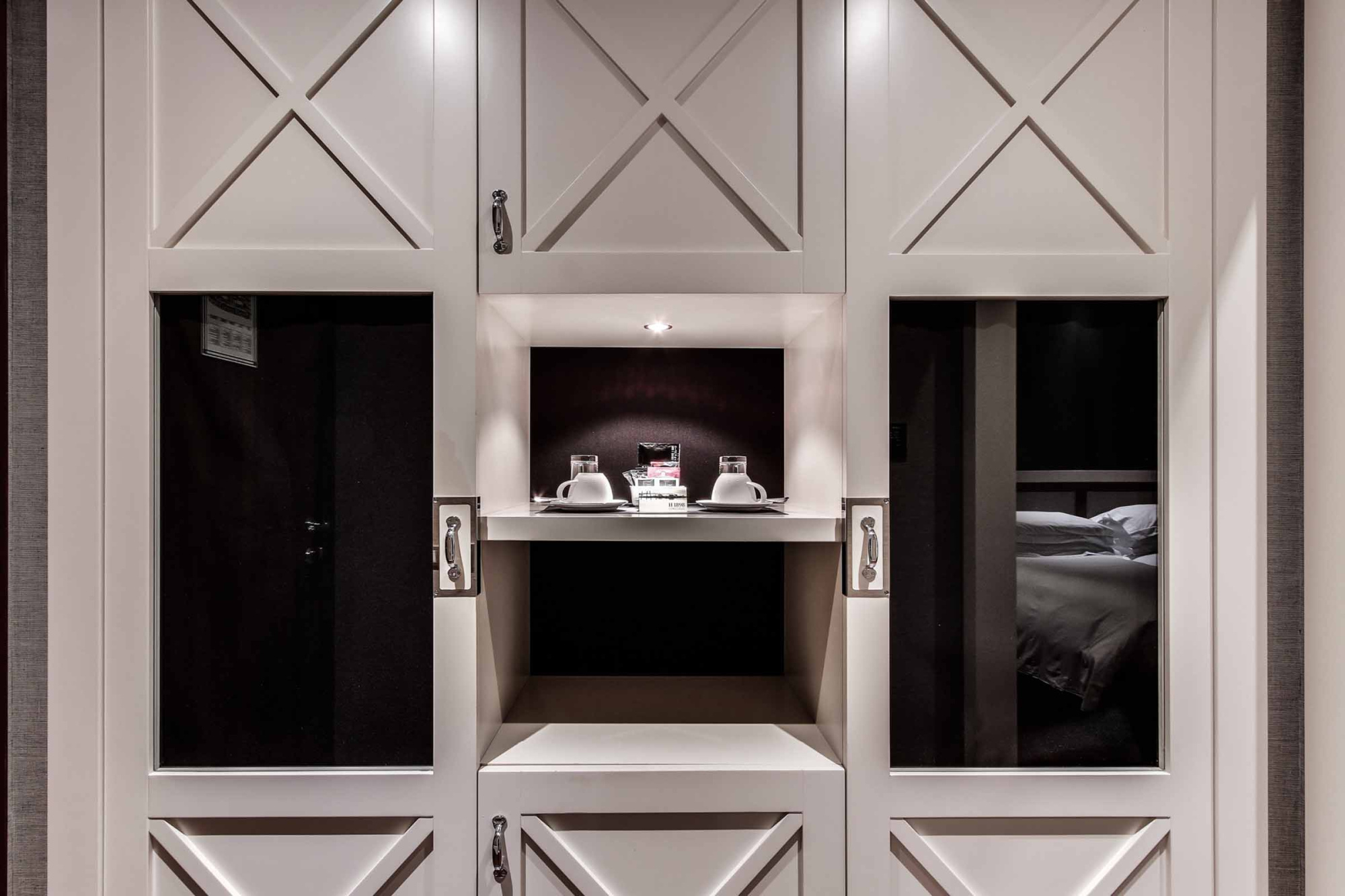 Se ve una pared con nicho decorativo y dos puertas abiertas que muestran camas en el interior.