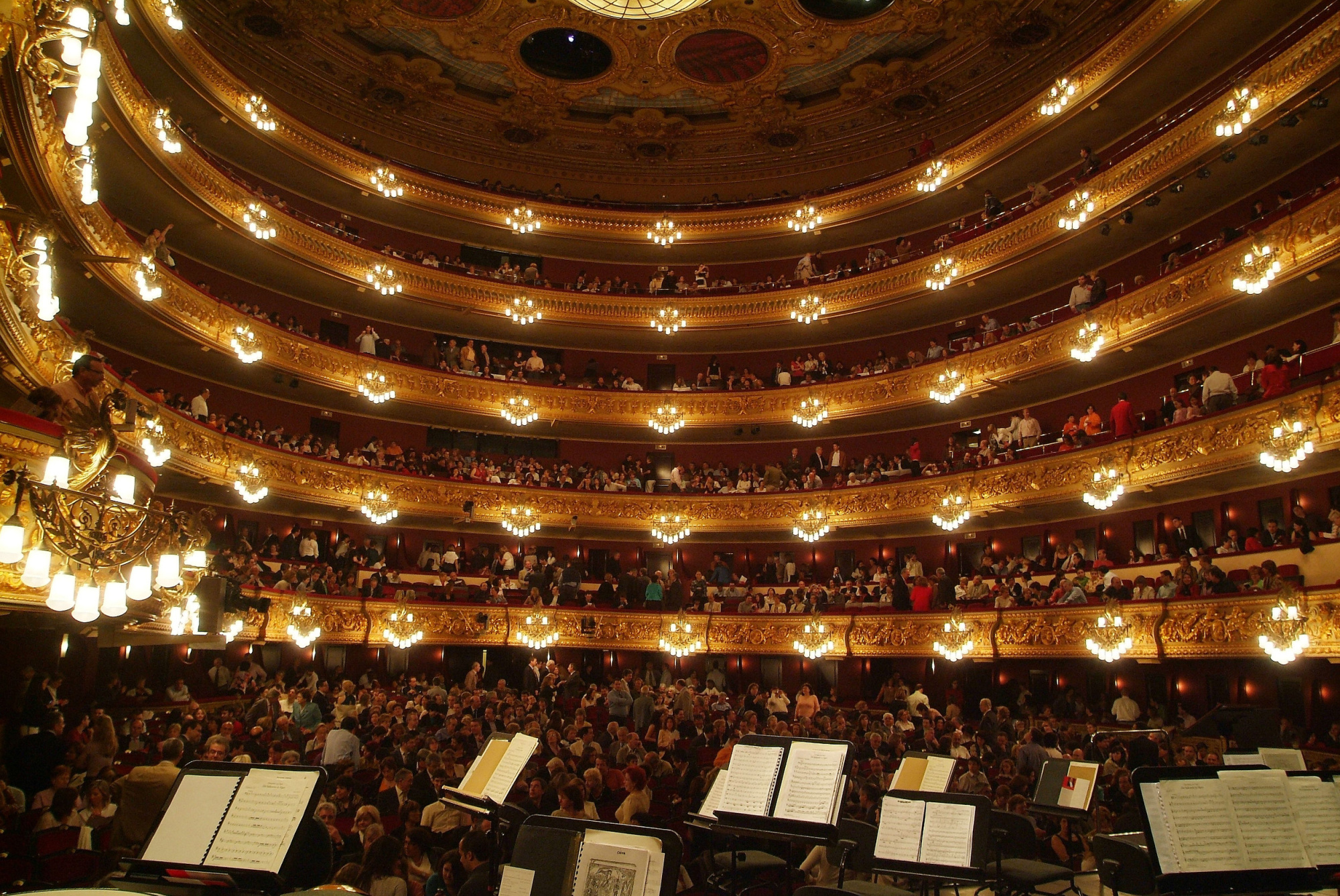 Se ve el interior de un teatro con butacas y filas de luces sobre el escenario.