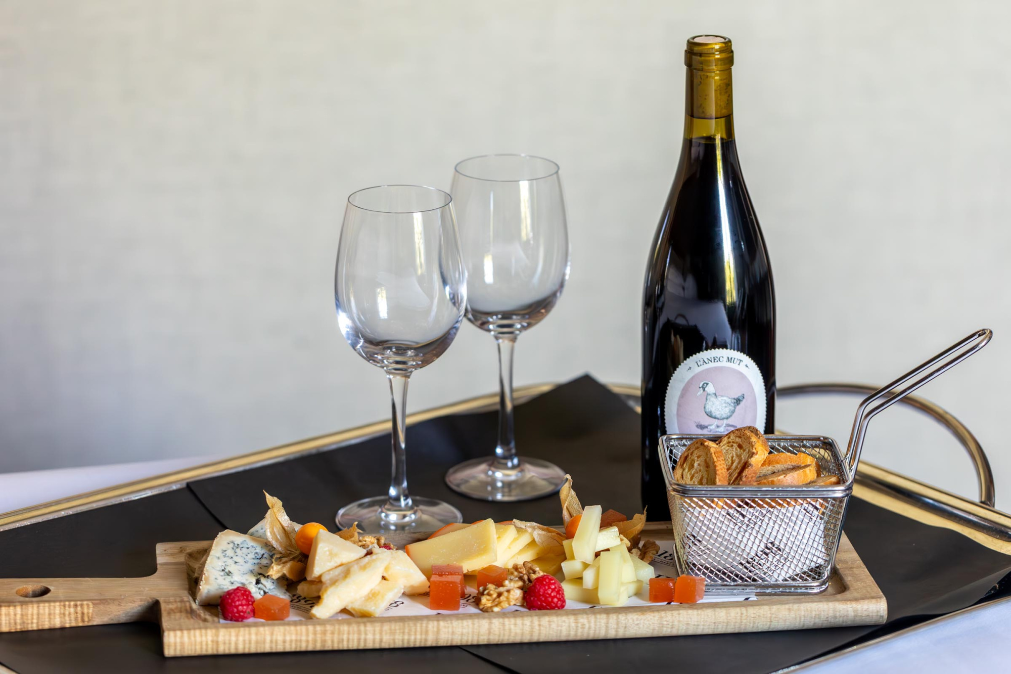 Una elegante presentación de una copa de vino tinto y una tabla de quesos variados, ideal para disfrutar en un ambiente sofisticado y acogedor.