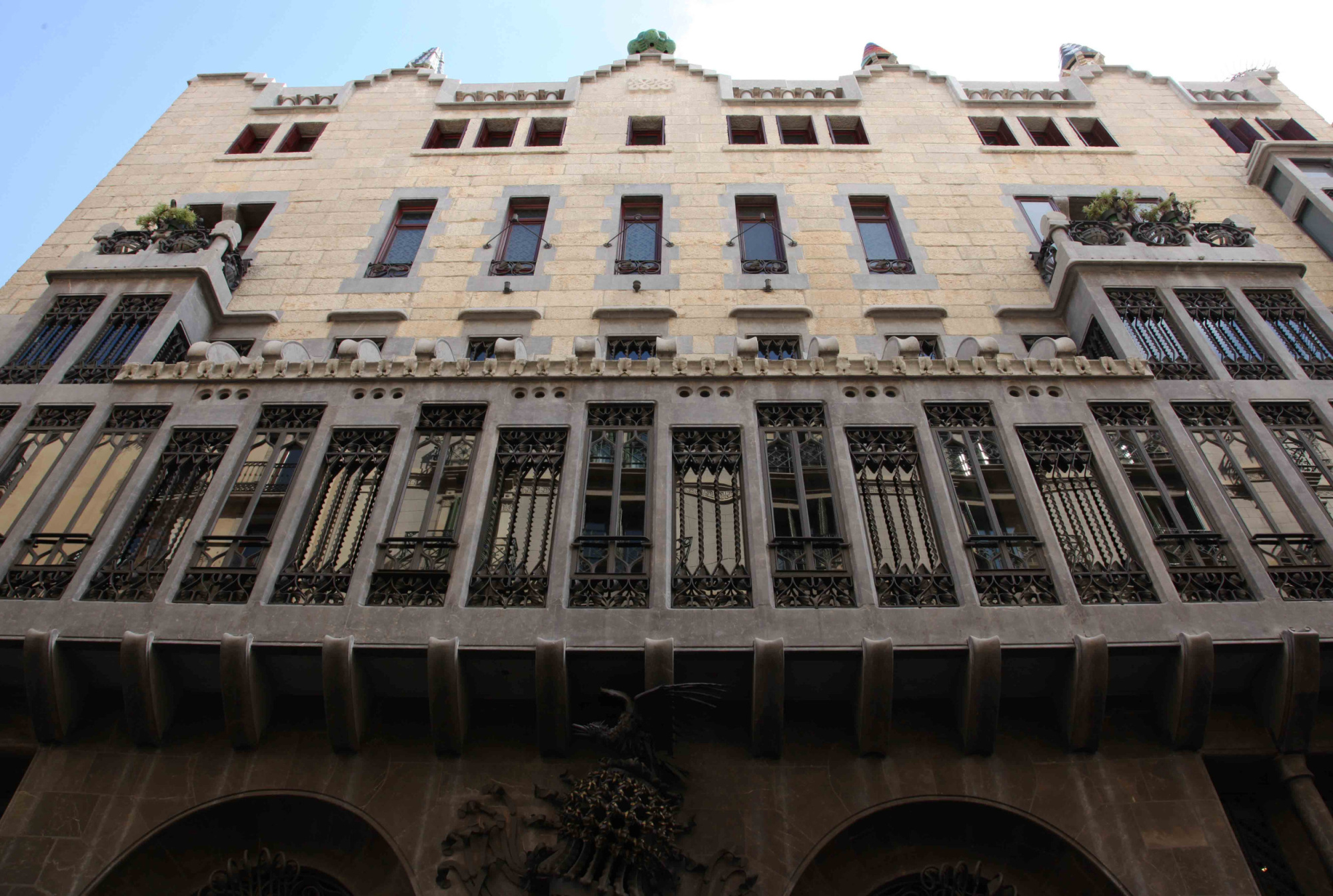 Se ve la fachada de un edificio de piedra con ventanas y arcos en la planta baja.