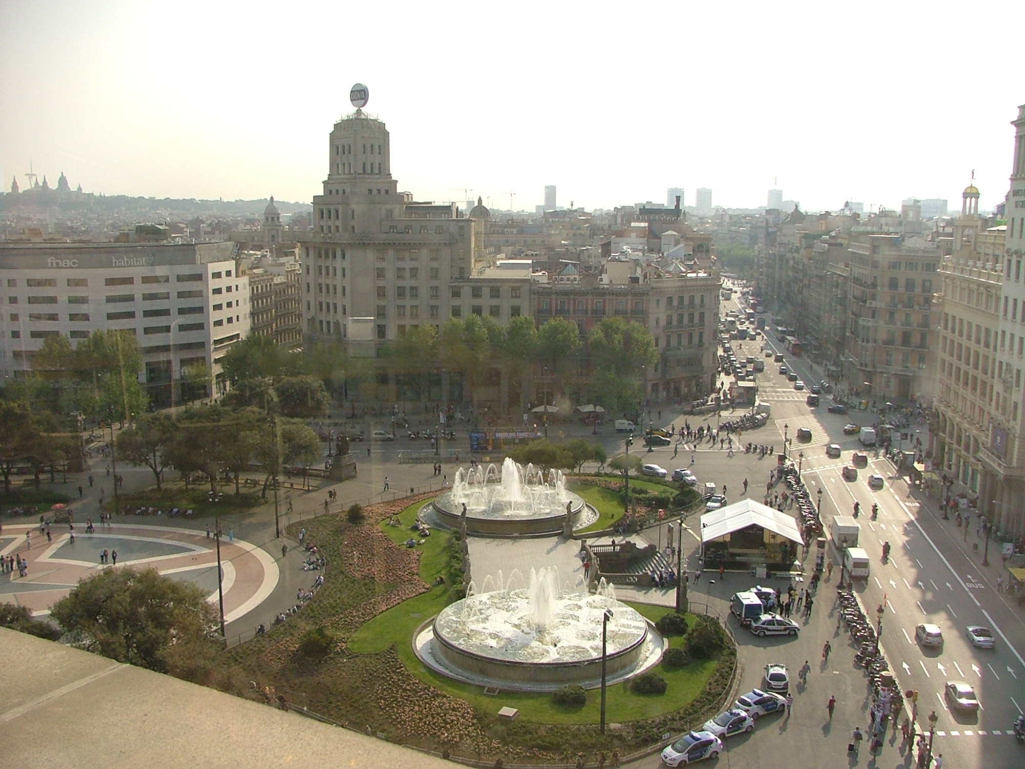 Vista panorámica de la plaza con una fuente circular y edificios alrededor.
