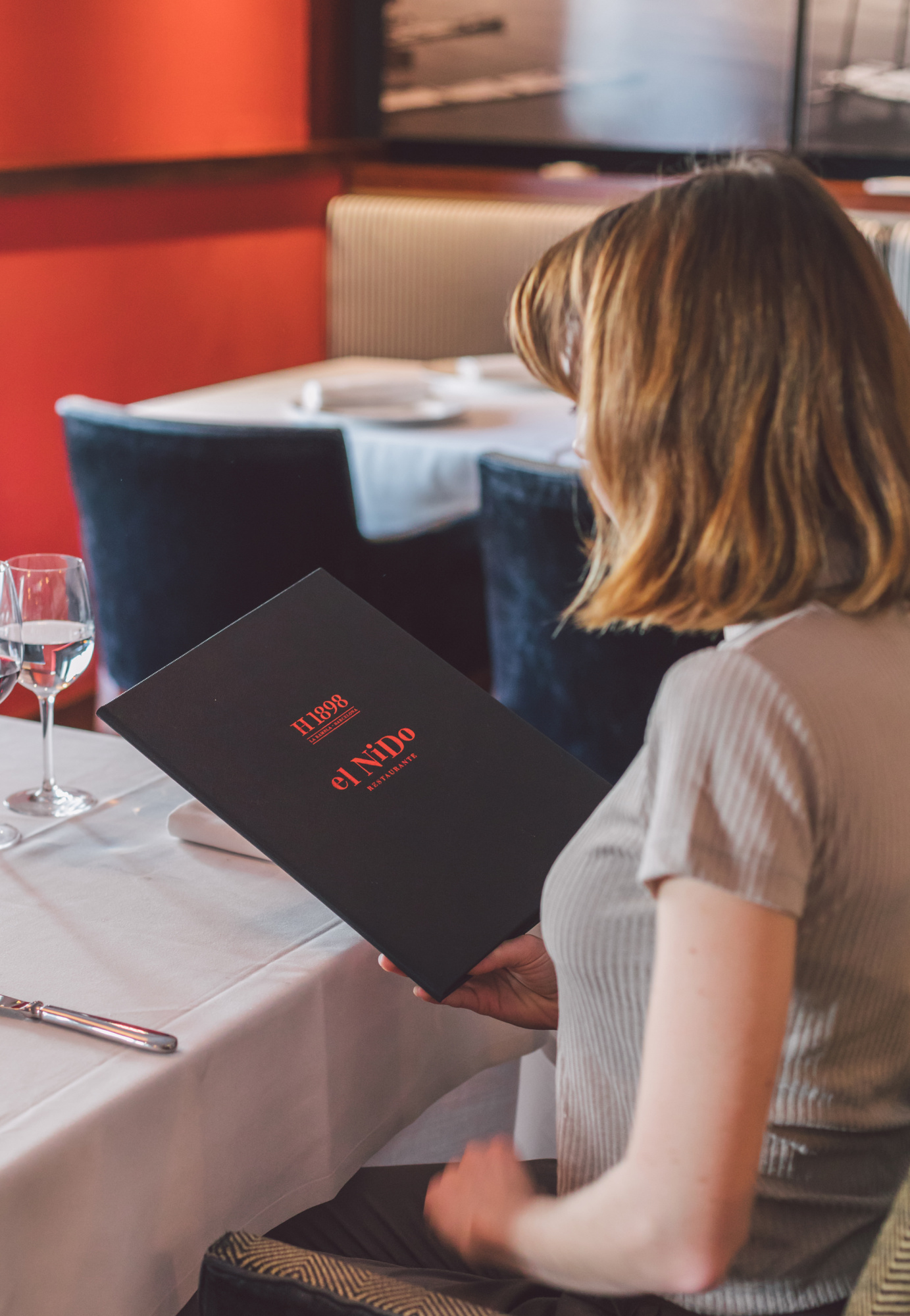Una persona se sienta en una mesa con mantel y tarjeta negra en un restaurante.