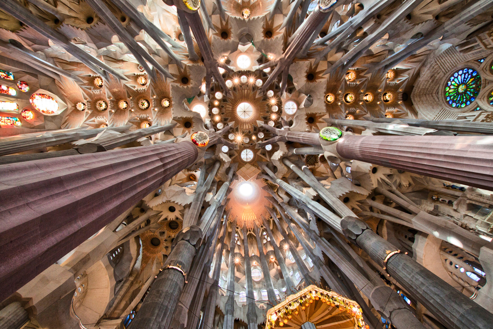 Se ve el interior de la basílica con columnas y vitrales bajo una bóveda decorada.