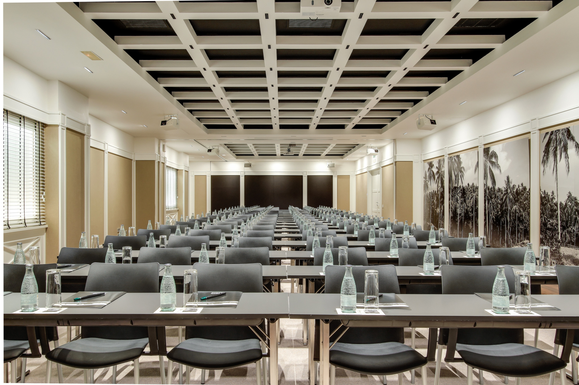 La sala de reuniones muestra mesas con sillas y pantallas de proyección al fondo.