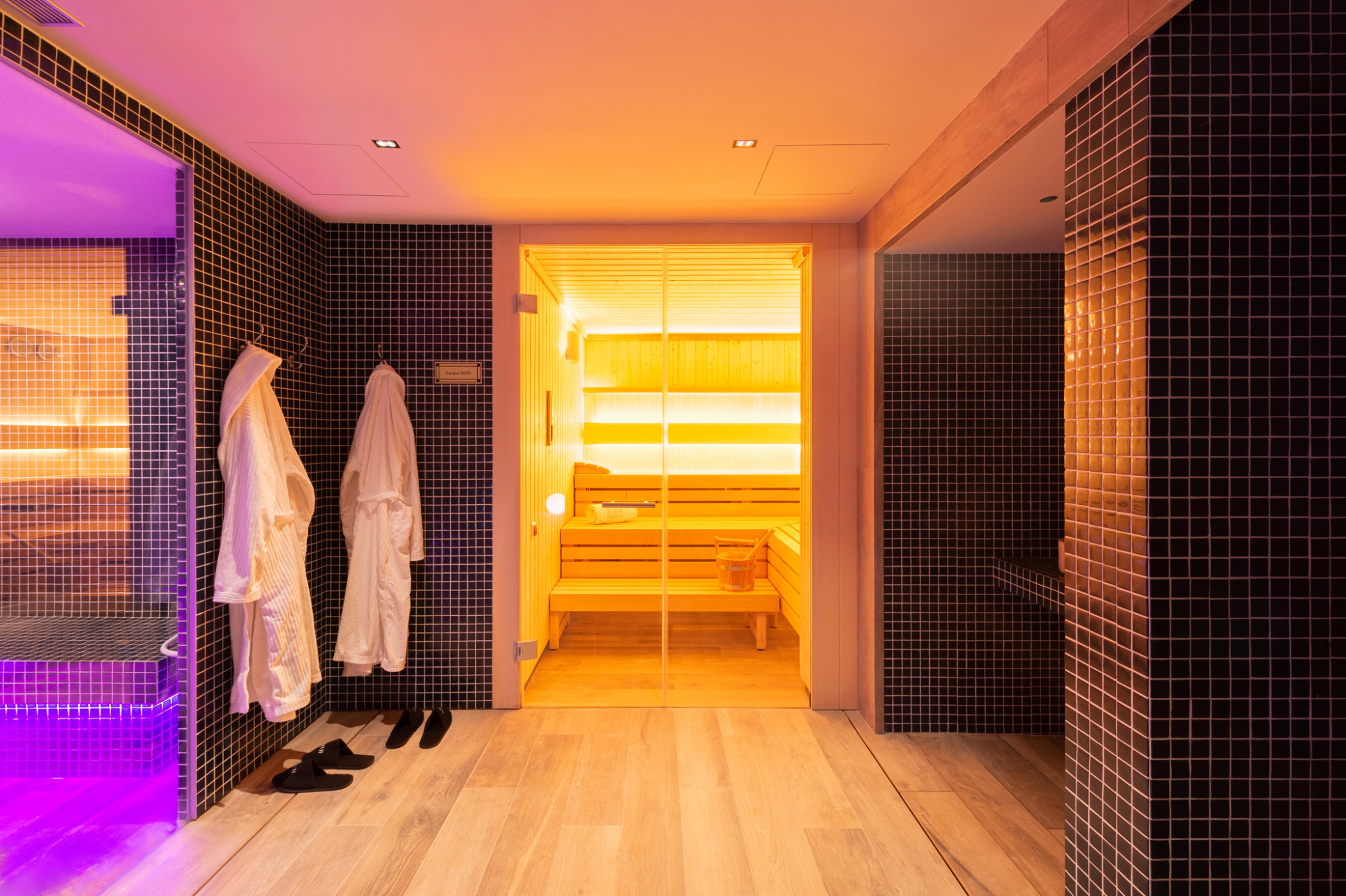 Una imagen que muestra una sauna de spa elegante y moderna, con un ambiente relajante y decoraciones minimalistas. La iluminación suave y los detalles en tonos neutros crean un espacio acogedor para el bienestar.