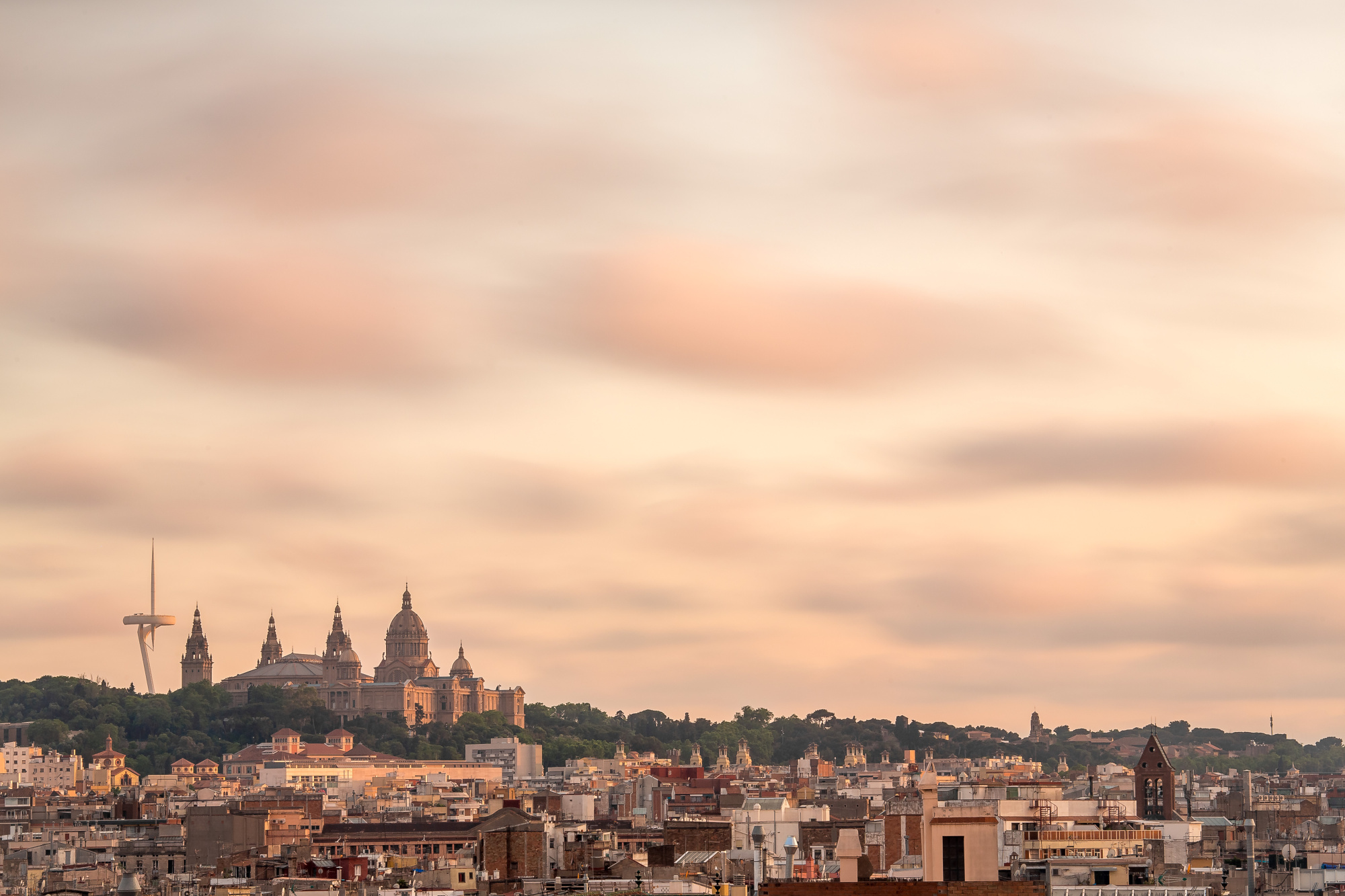 Se ve un panorama urbano con edificios y un cielo nublado al atardecer.
