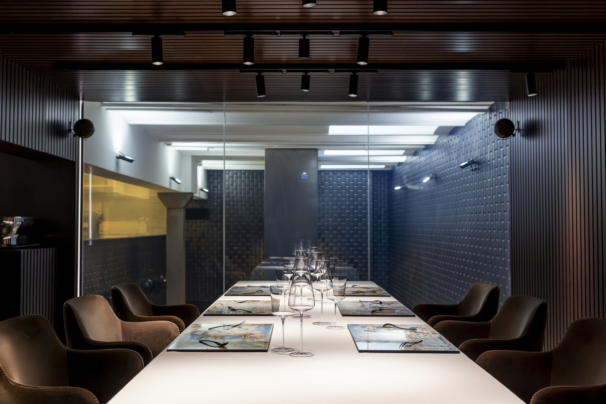 Se ve una sala de reuniones con una mesa larga y sillas alrededor, iluminada por focos del techo.