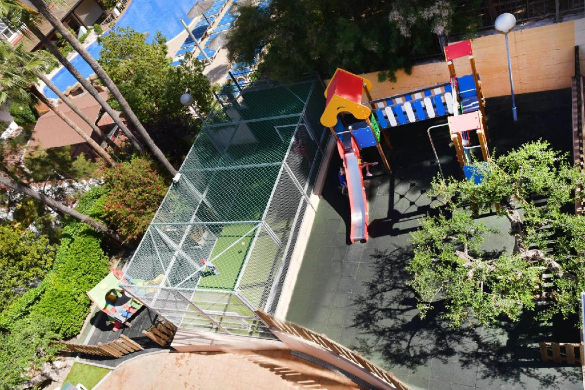 Vista panorámica desde arriba del edificio del Aparthotel SunClub Salou, mostrando la zona de juegos al aire libre en un entorno vacacional.