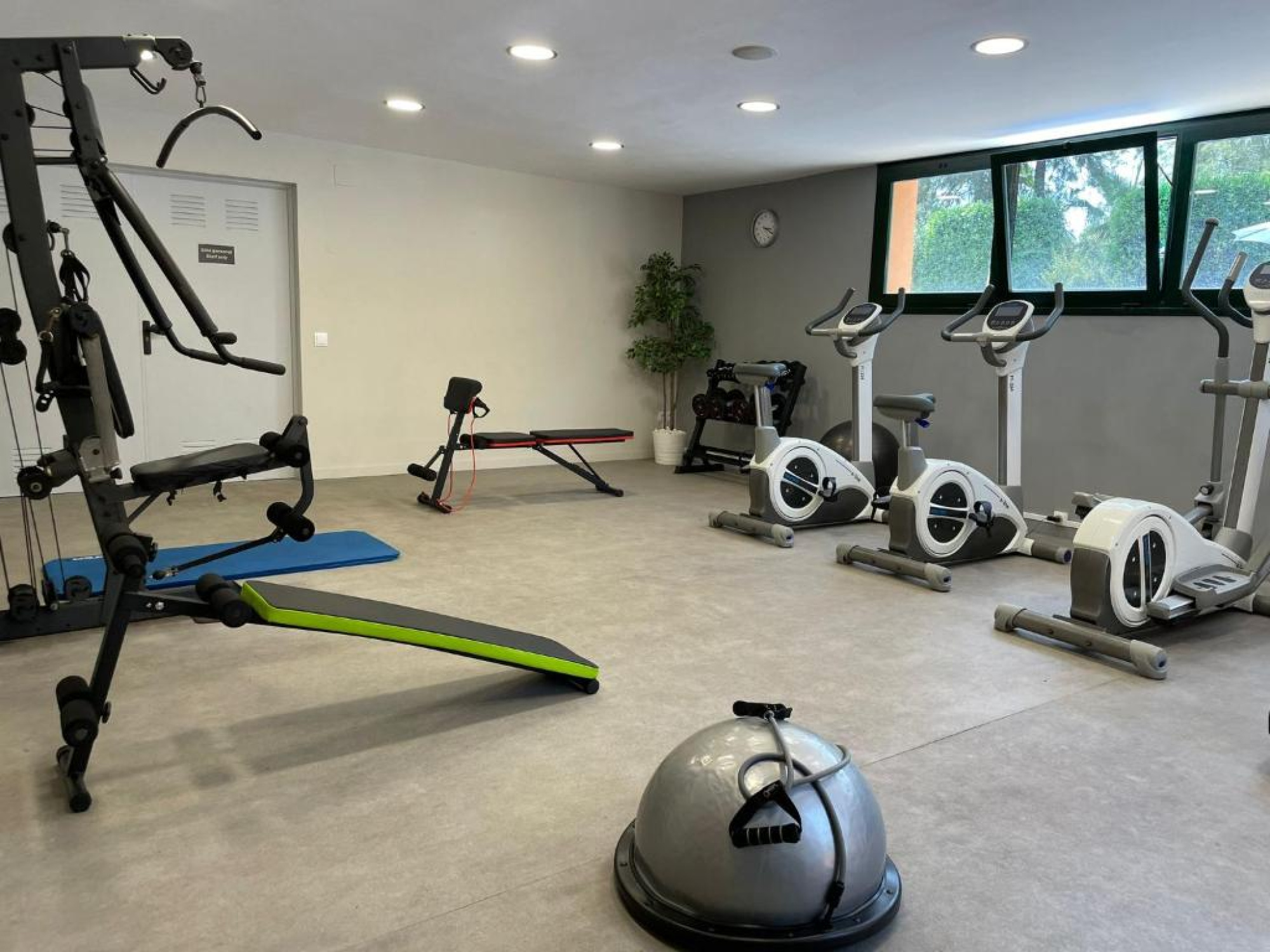 El gimnasio cuenta con varias máquinas de ejercicio modernas en un ambiente luminoso y bien equipado, ideal para mantenerse en forma durante la estancia.