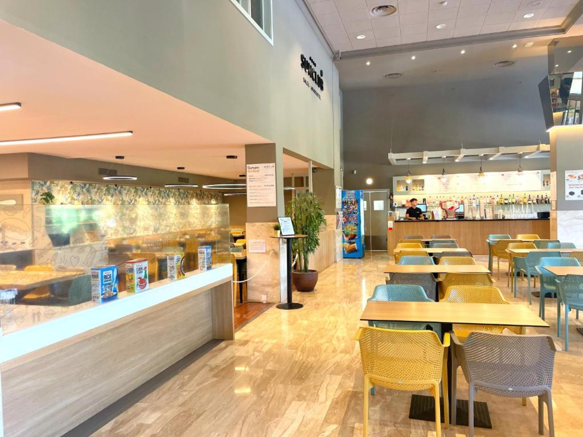 El restaurante presenta mesas y sillas de estilo moderno, con un bar en el fondo, creando un ambiente acogedor y contemporáneo para los huéspedes.