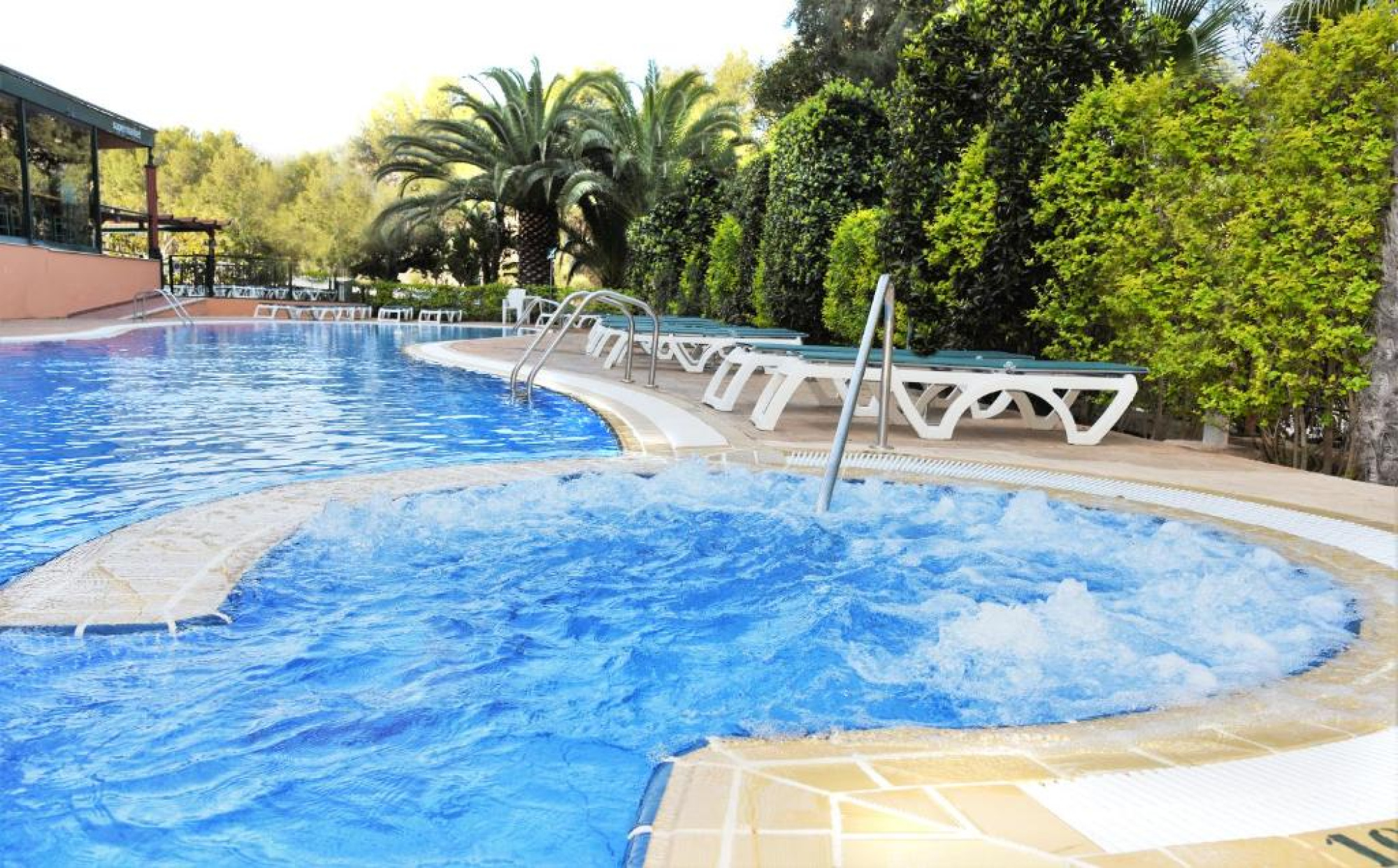 Una amplia piscina de color azul con mesas y sillas dentro del agua, ubicada en el Aparthotel SunClub Salou en Salou, ideal para relajarse y socializar.