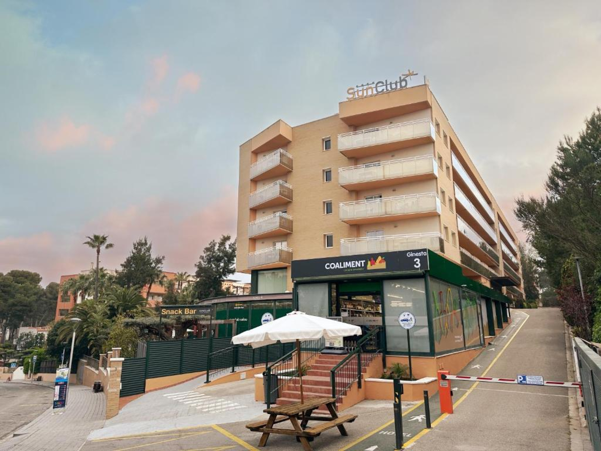 Edificio del aparthotel con una sombrilla en el frente, en Salou. La estructura es moderna, con colores claros y un diseño que invita a la relajación.