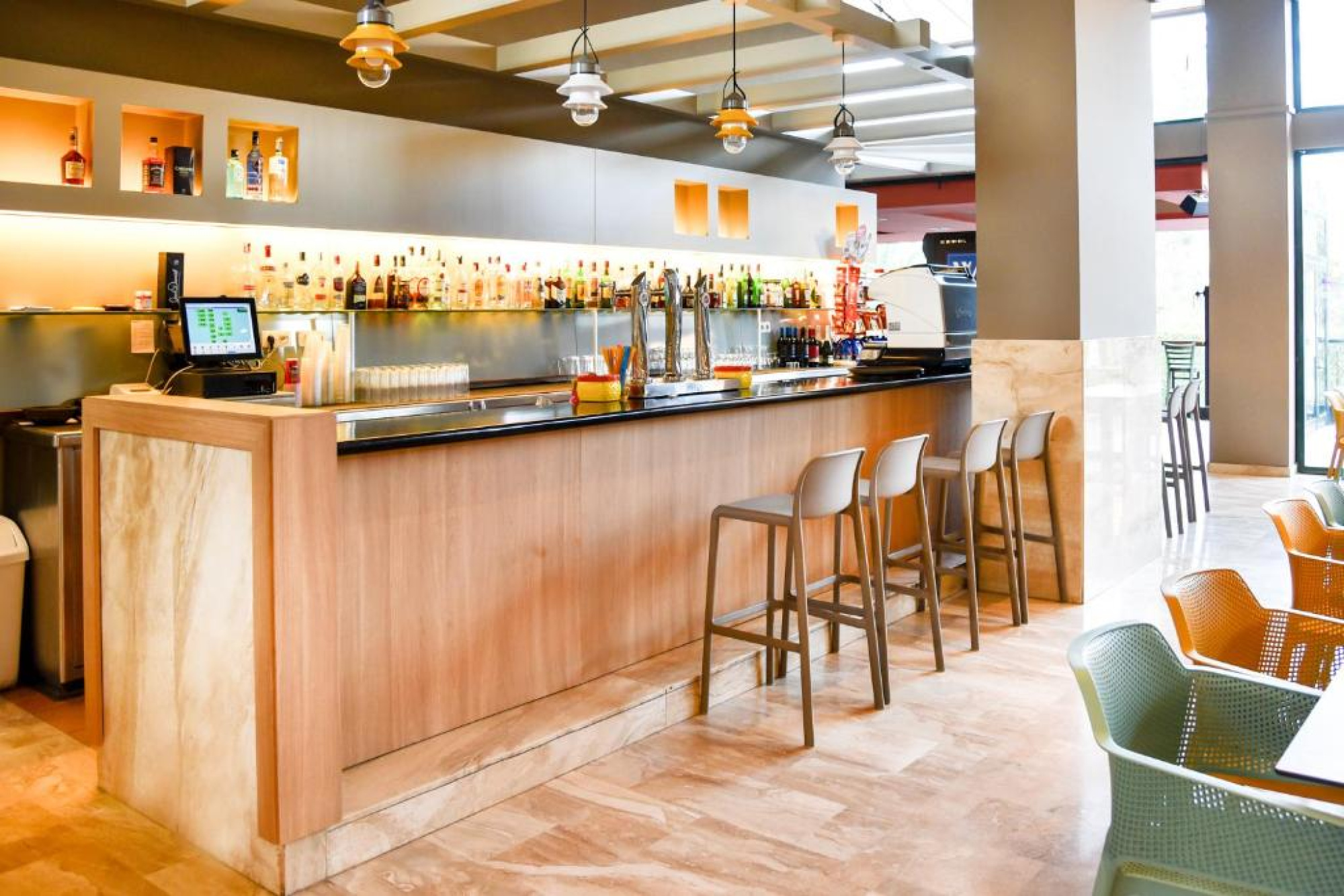 Un bar en un restaurante del Aparthotel SunClub Salou, equipado con taburetes en un ambiente moderno y acogedor, ideal para relajarse y socializar.