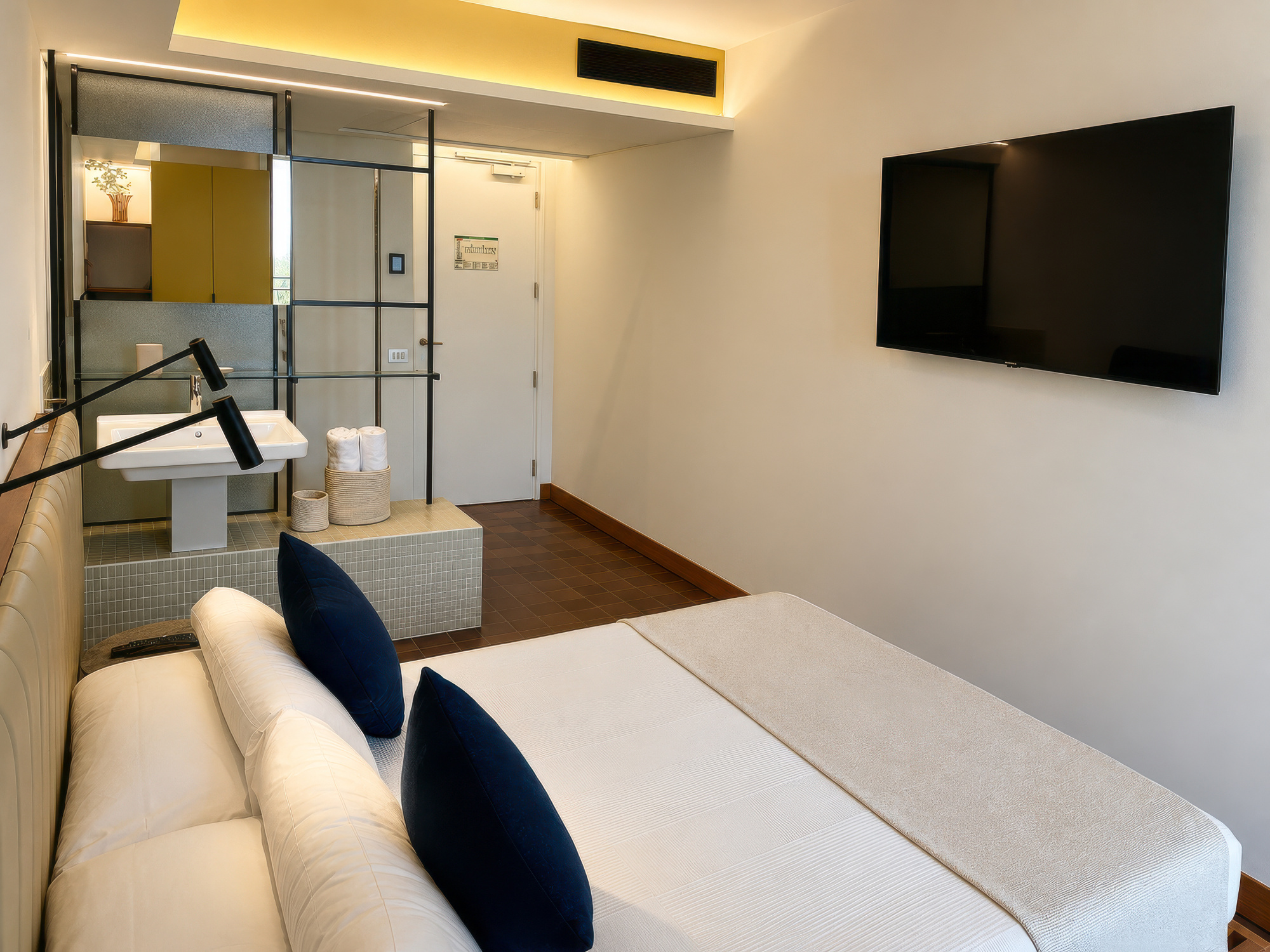 Se ve una cama doble con almohadas, un televisor de pared y una zona de descanso iluminada en el interior.