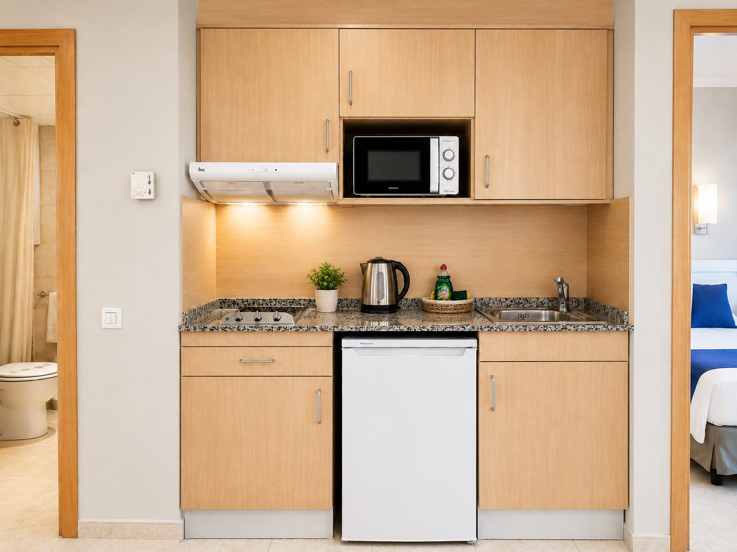 Se ve una cocina compacta con armarios de madera, encimera, fregadero y microondas empotrado.