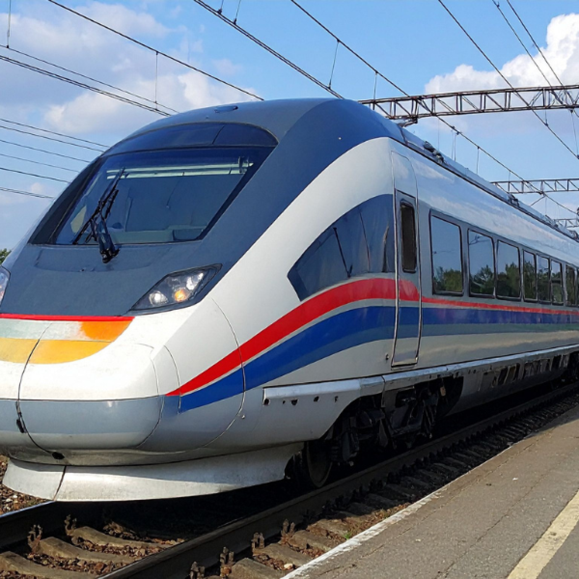 Un tren de alta velocidad está detenido en un andén junto a las vías.