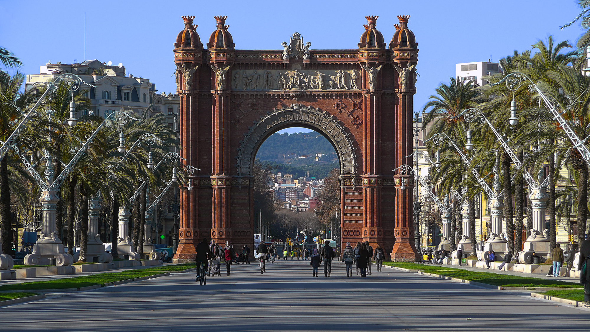 Se ve el arco de triunfo con palmeras y una avenida al frente bajo un cielo despejado.